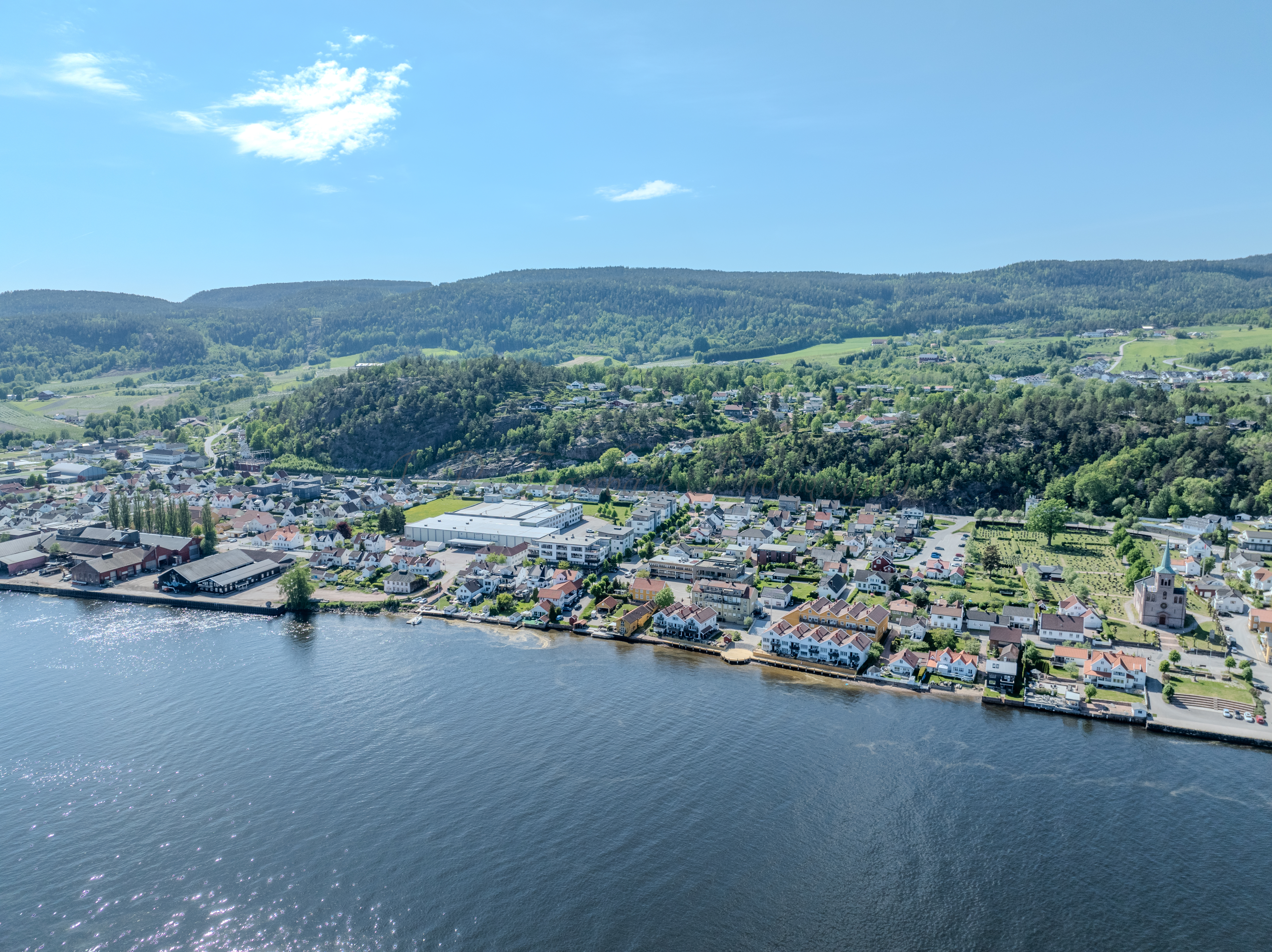 Buildings on both sides of a fjord where a ferry and other smaller boats are sailing