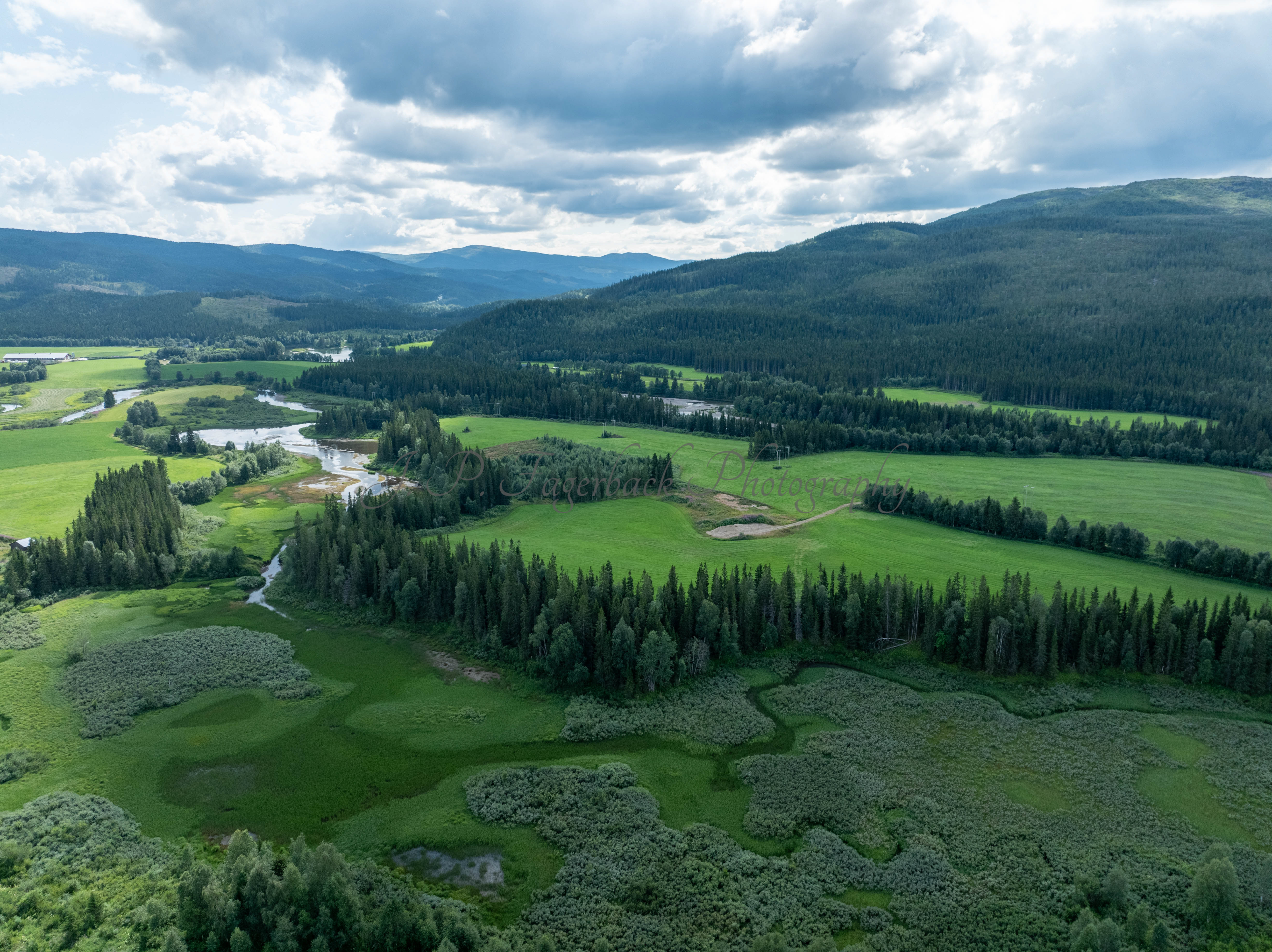An old airstrip  and fields with buldings beyond it and mountains on the background where one looks like a hat