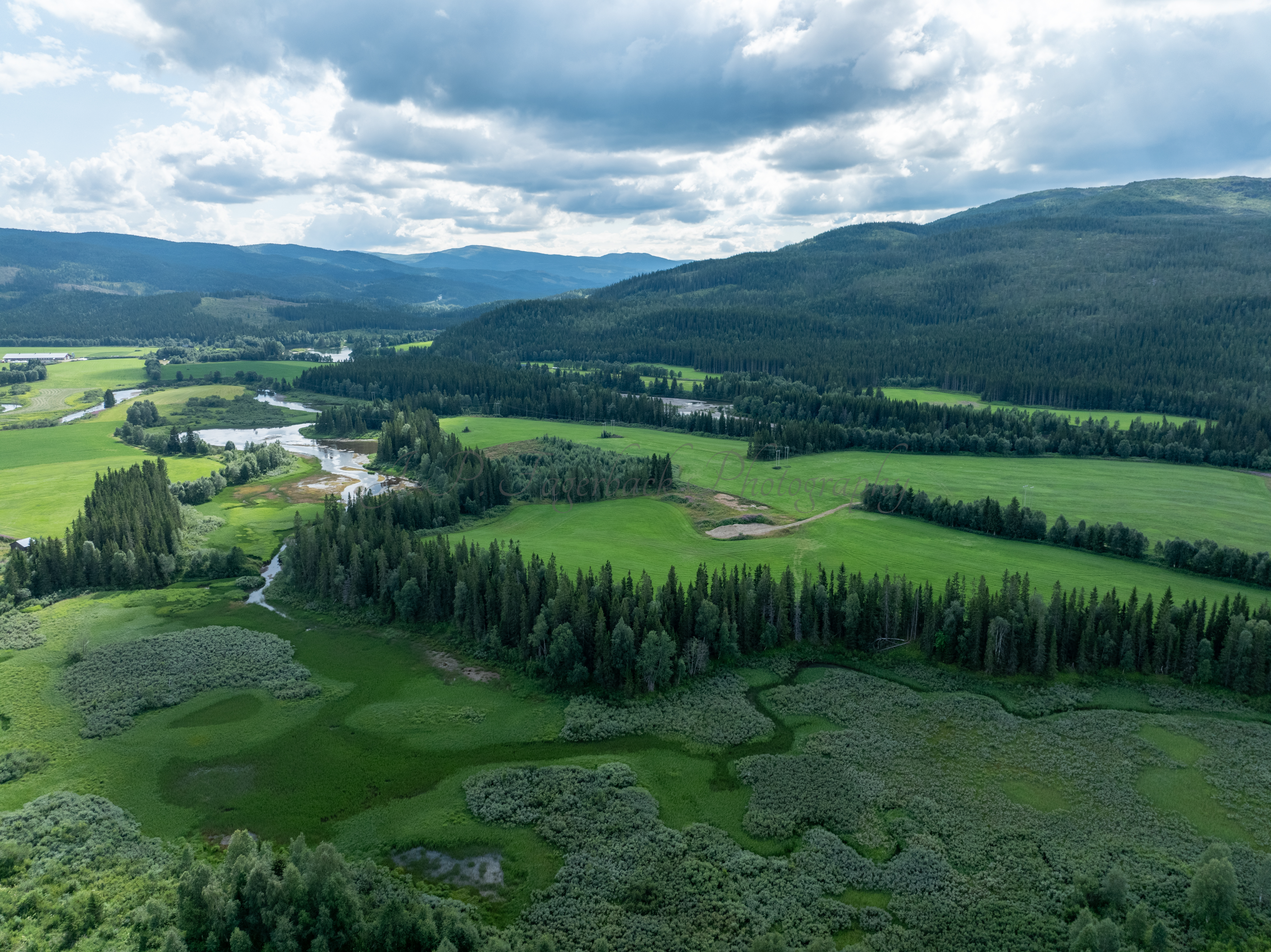An old airstrip  and fields with buldings beyond it and mountains on the background where one looks like a hat