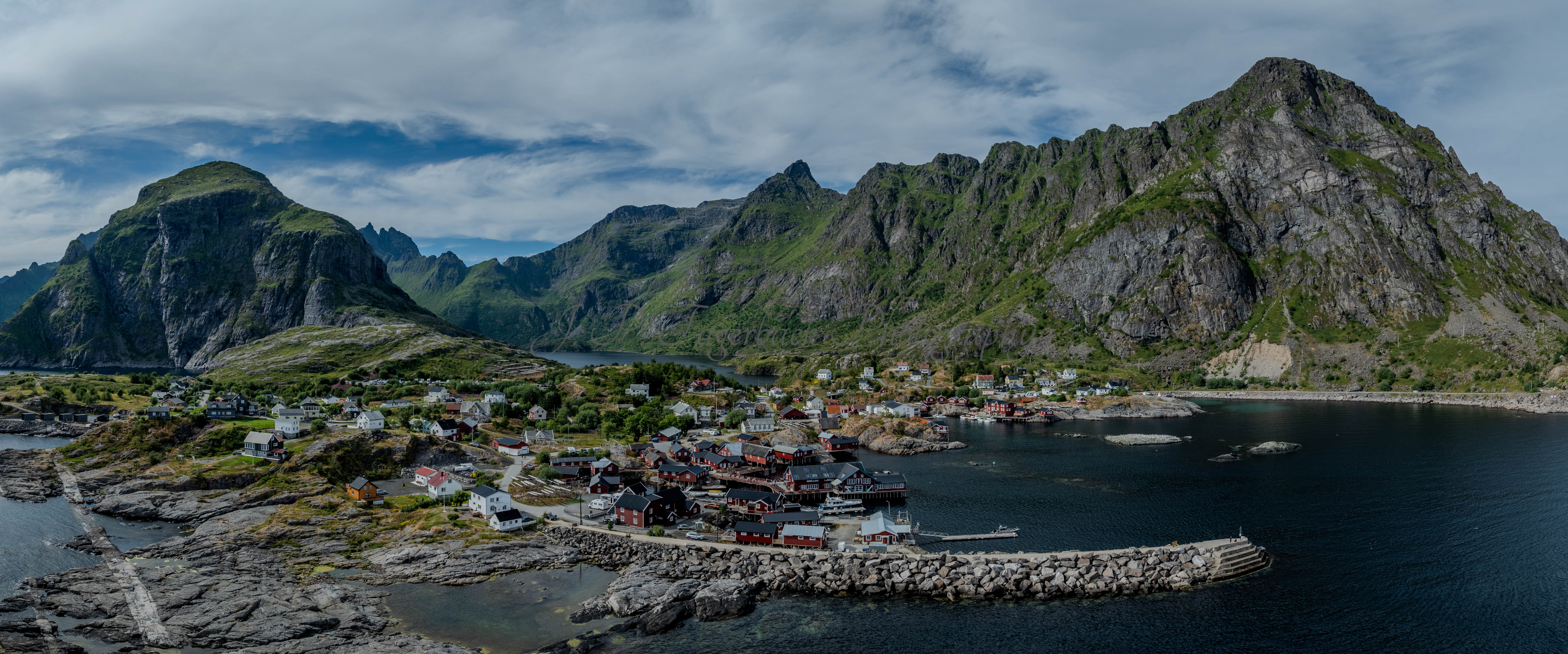 Buildings along the shore of a body of water with a mountain in the background on a gray day