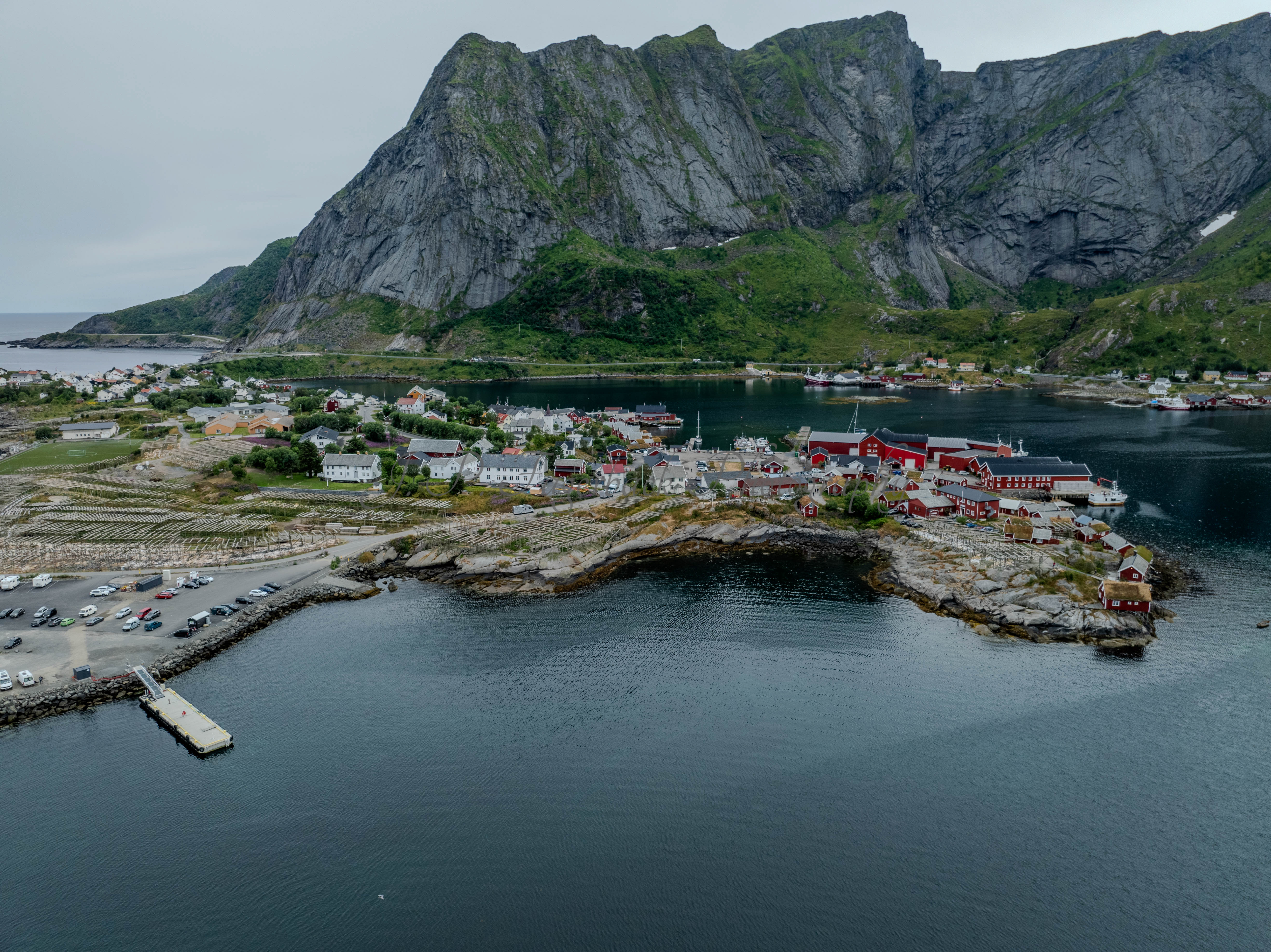 Buildings along the shore of a body of water with a mountain in the background on a gray day
