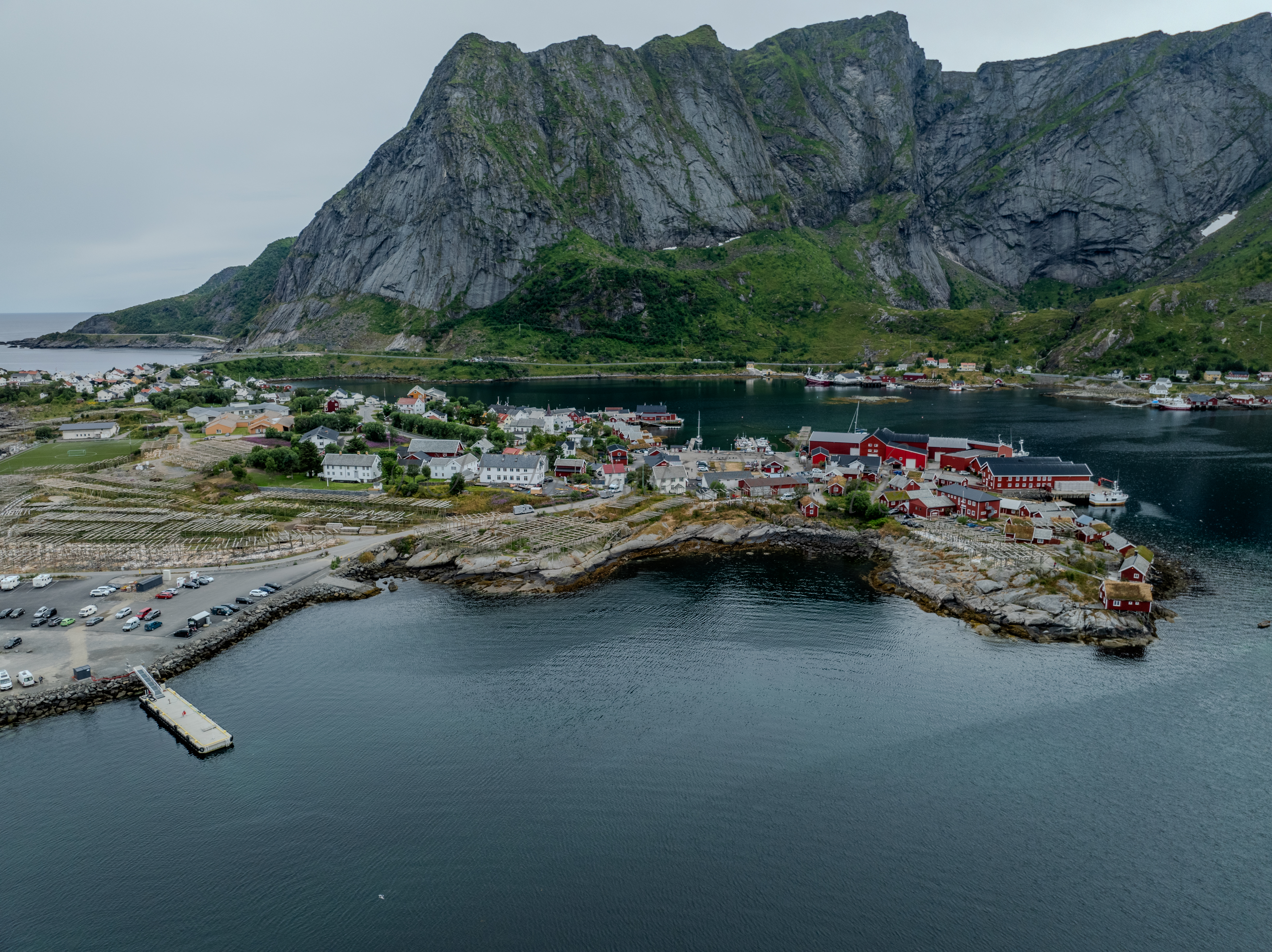 Buildings along the shore of a body of water with a mountain in the background on a gray day