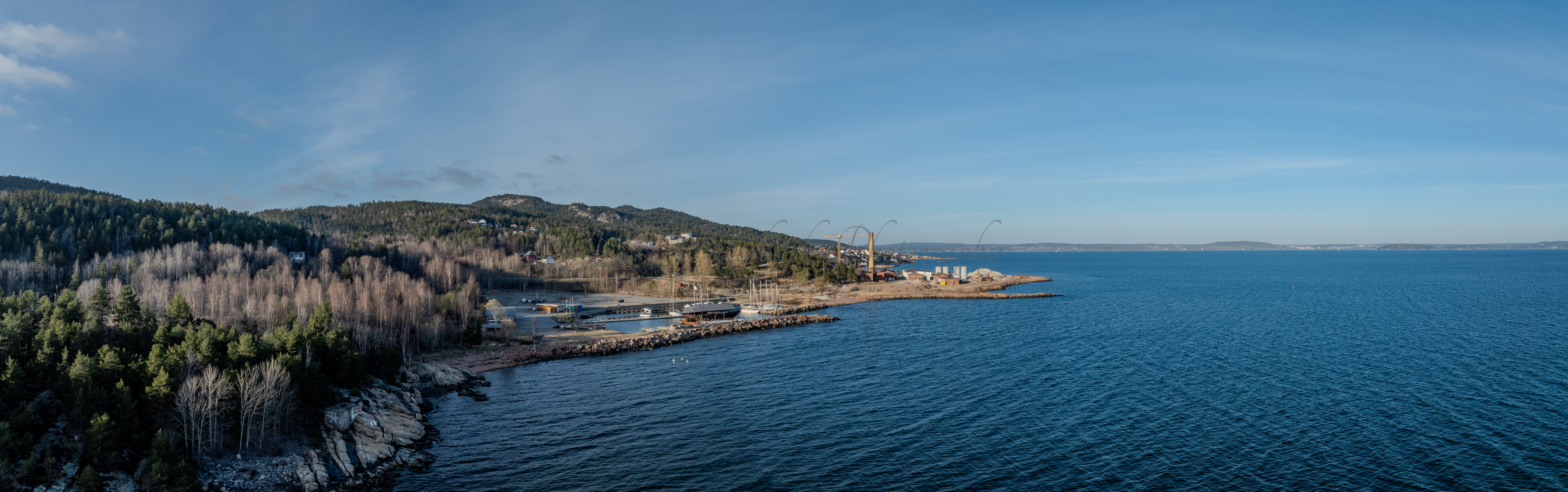 An old ship  wreck with a protection roof over it in a marina by a large body of water under a blue sky