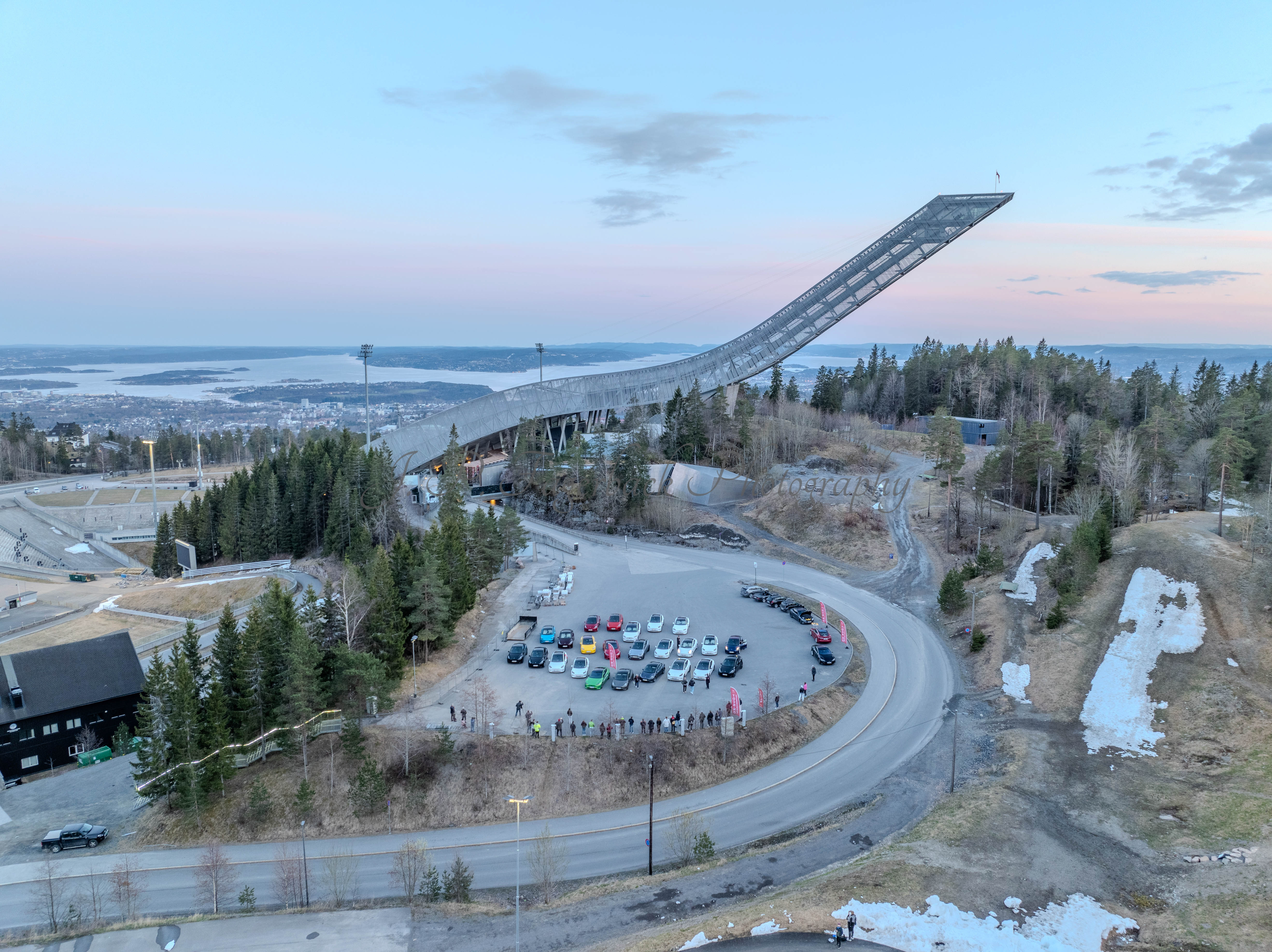 Cars on a parking lot from upon high with a ski jump in the background