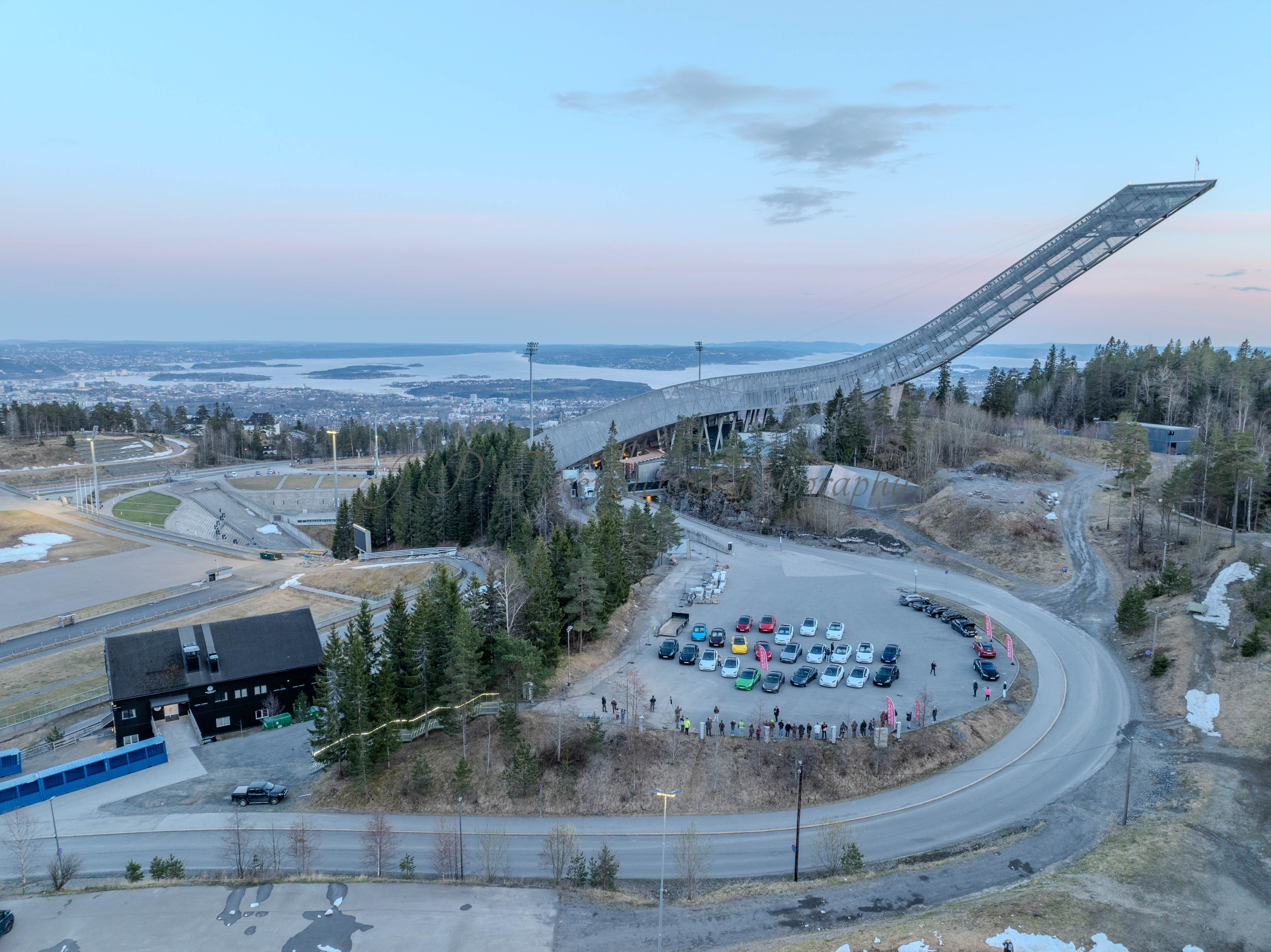 Cars on a parking lot from upon high with a ski jump in the background