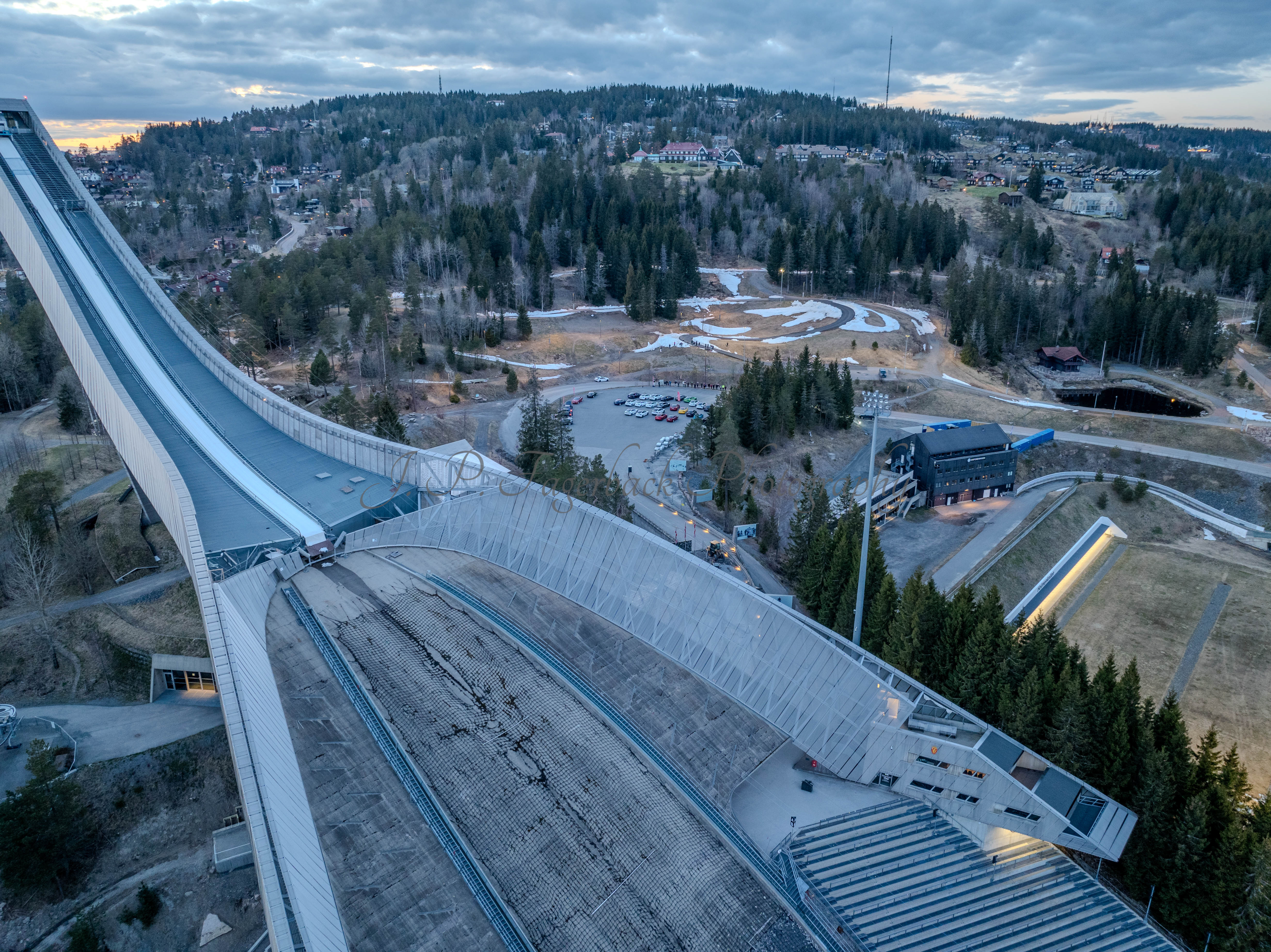 Cars on a parking lot from upon high with a ski jump in the background