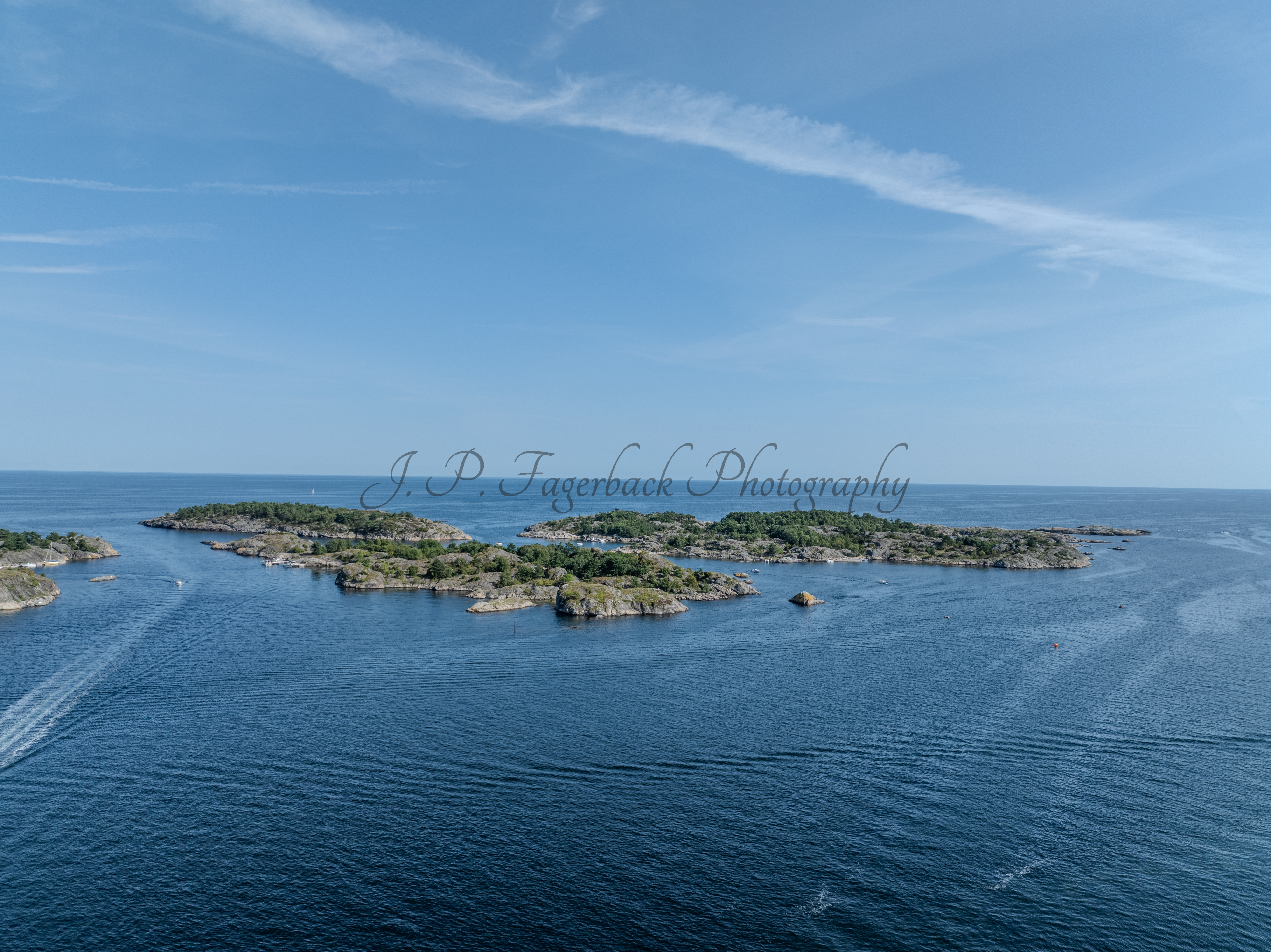Islands with green vegitaions in sourounded by blue ocean water under a blue sky