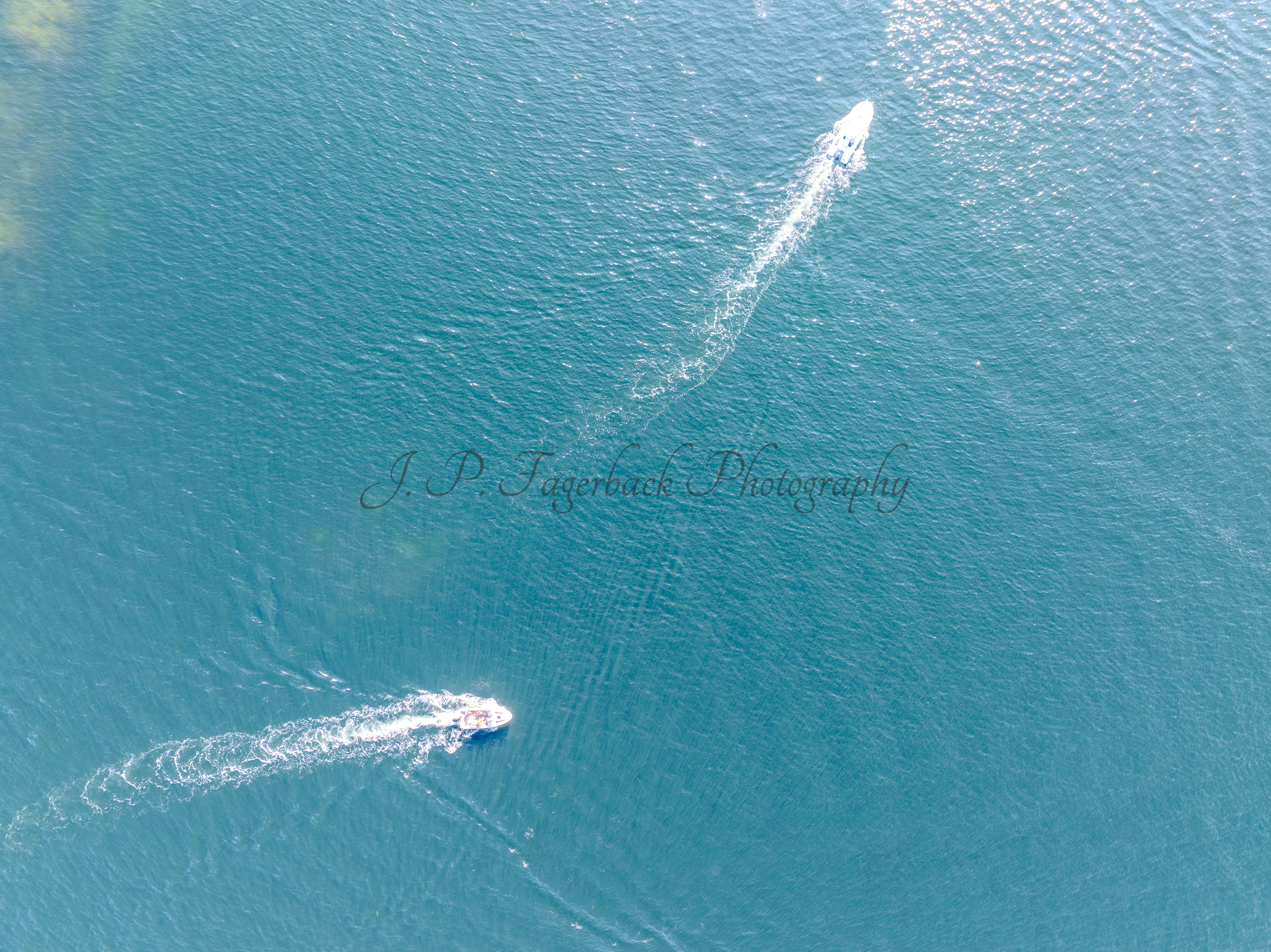 Boats in a blue sea making wakes