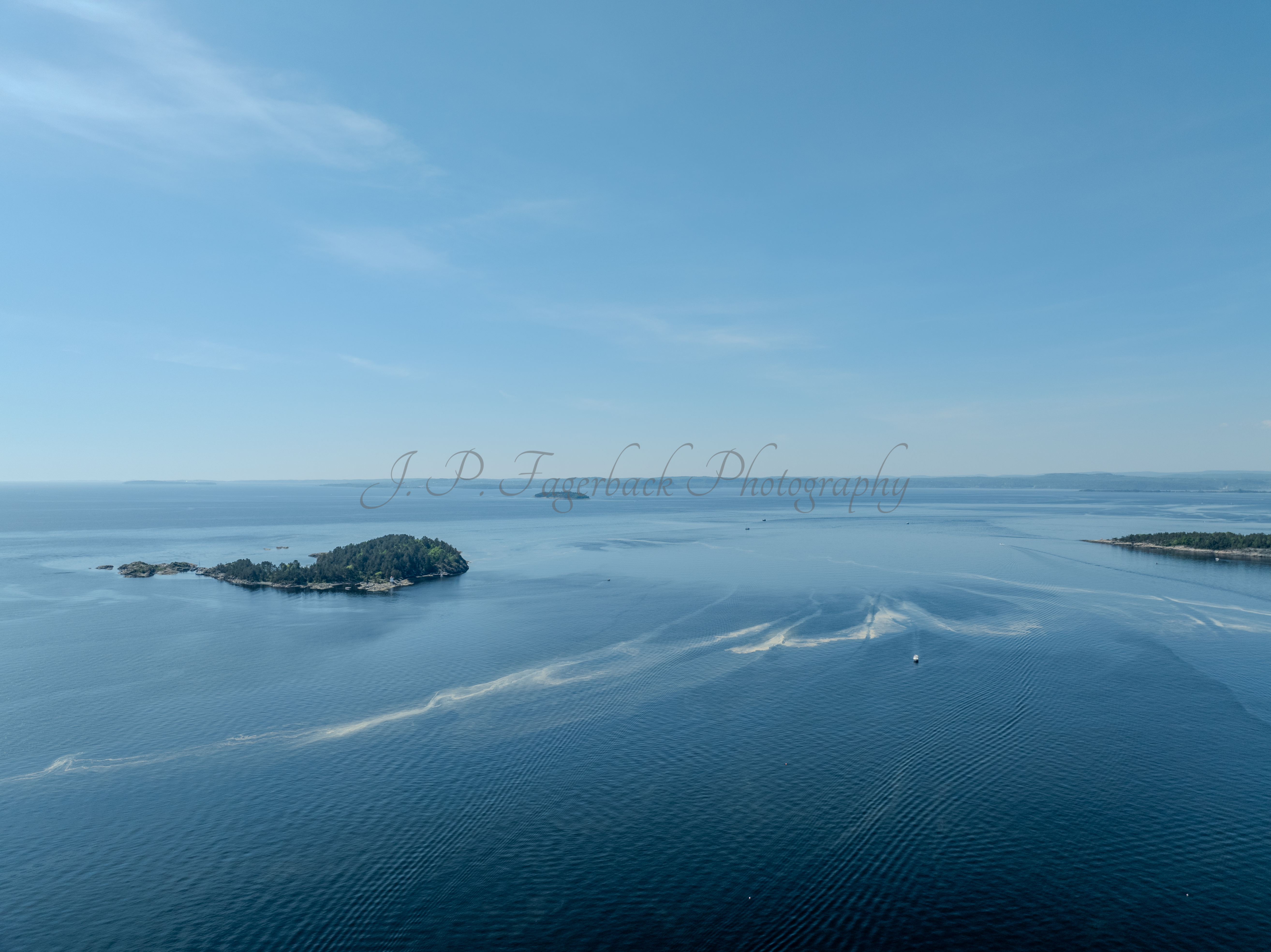 An old ship  wreck with a protection roof over it in a marina by a large body of water under a blue sky