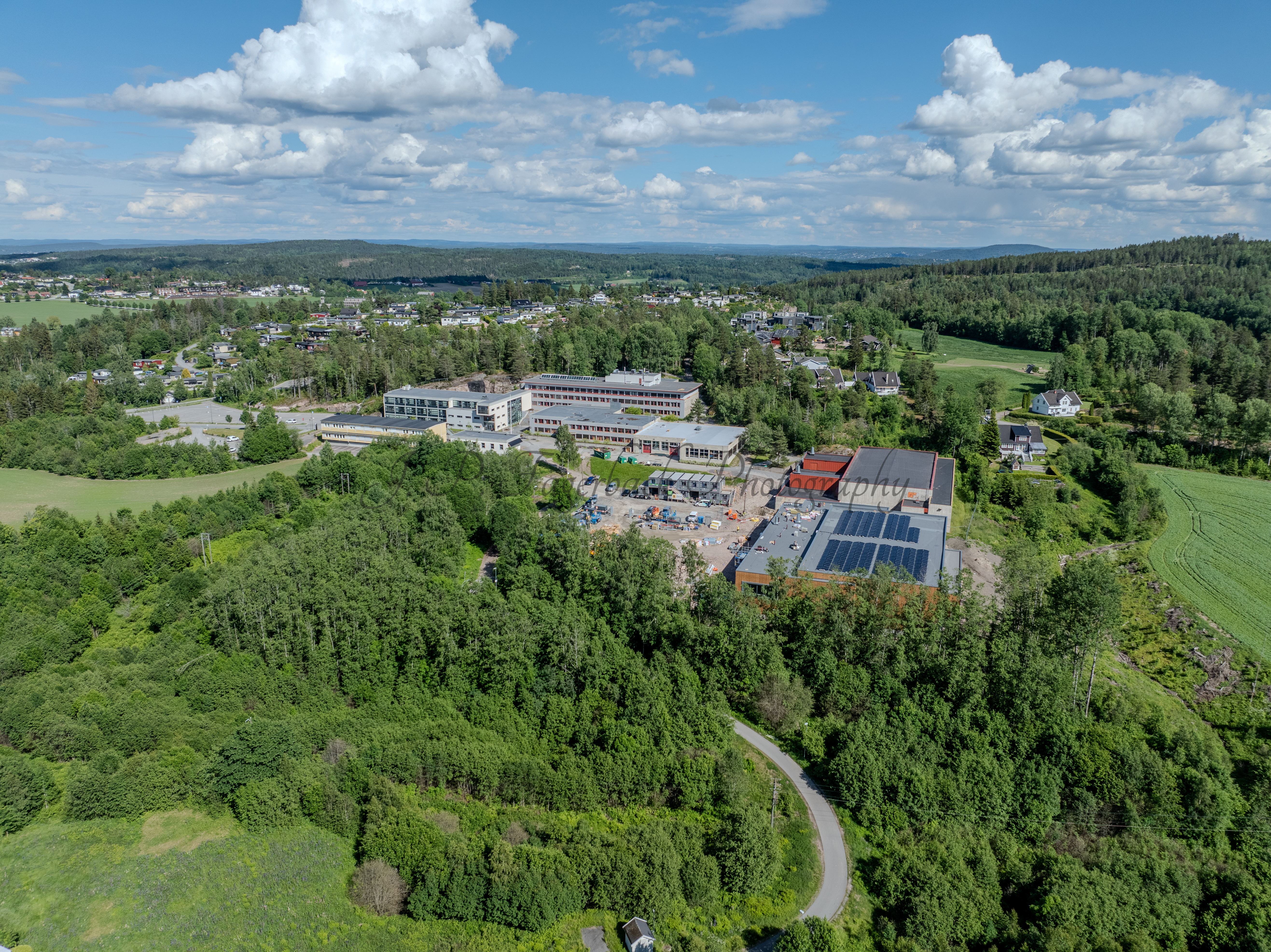 Buildings in a wooded green area under a partially clouded blue sky