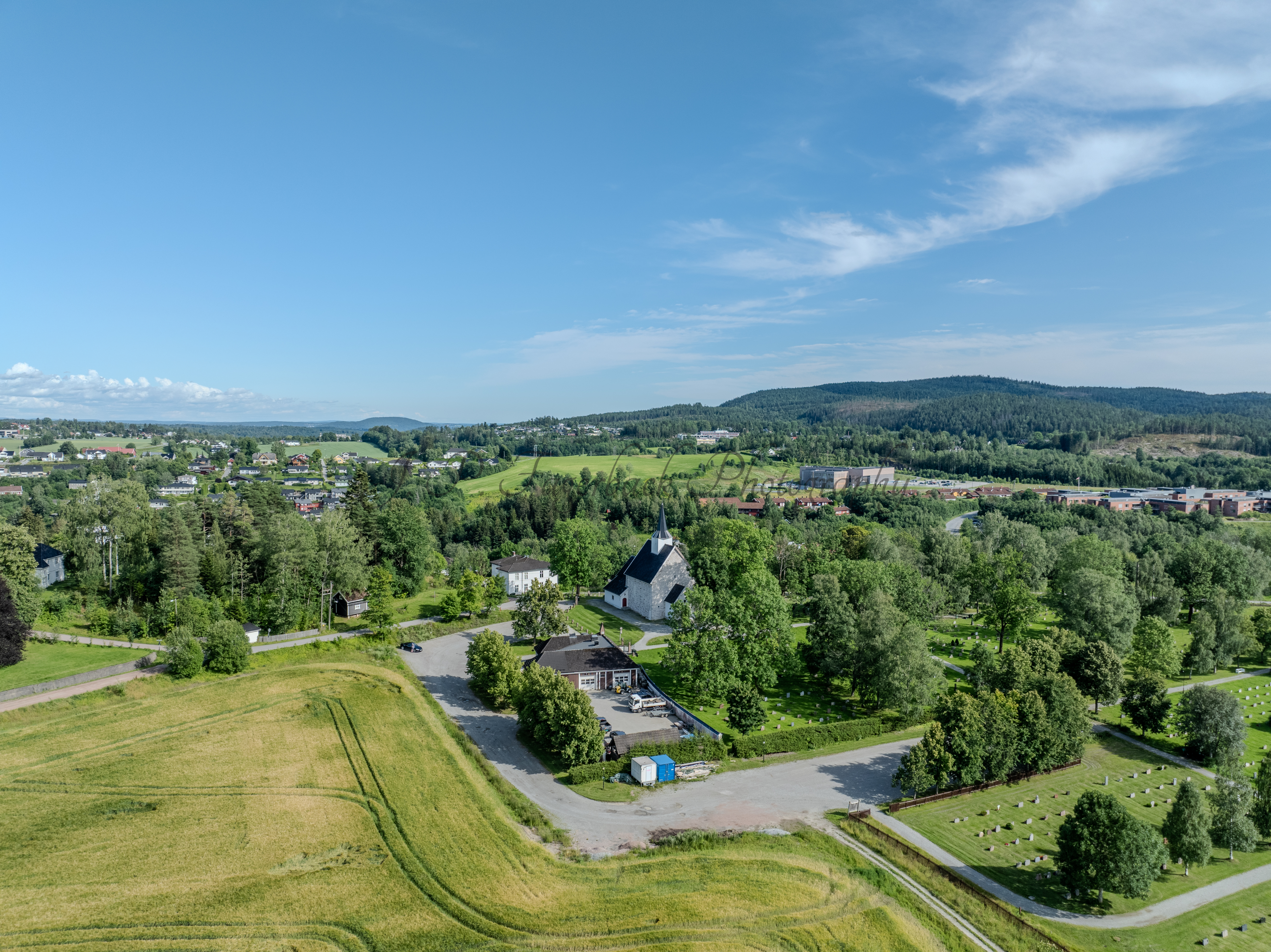 White stone church in background of a green landscape under a blue sky