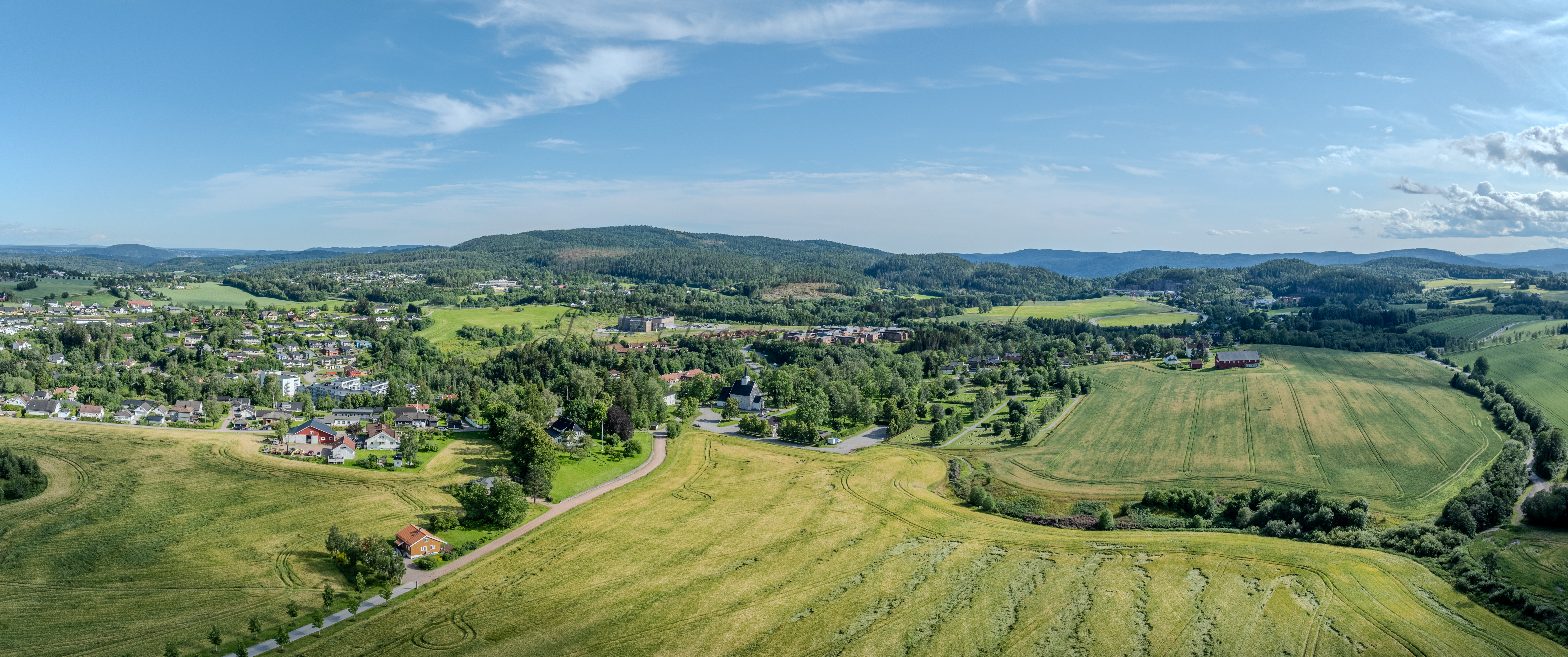 White stone church in background of a green landscape under a blue sky