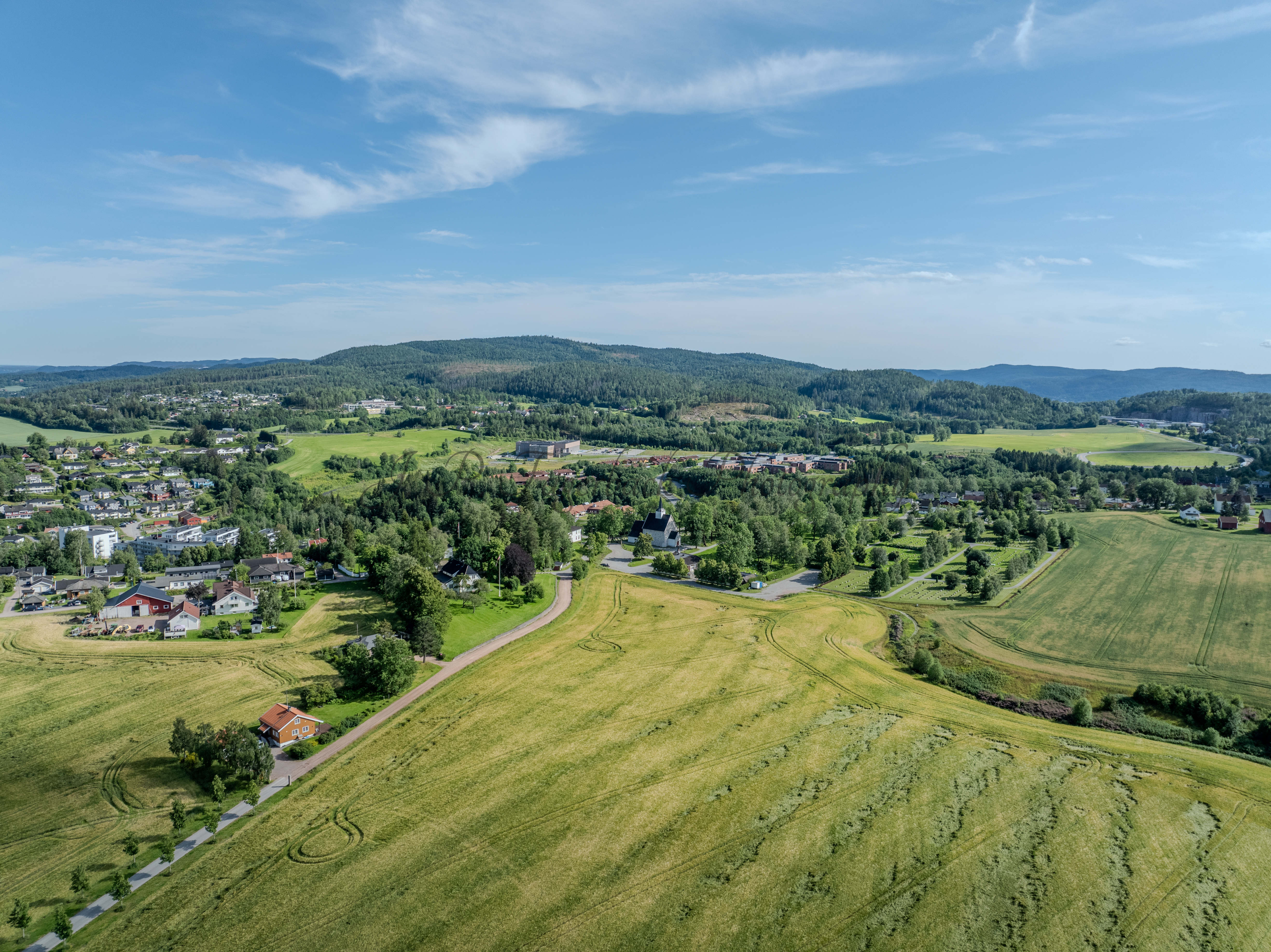 White stone church in background of a green landscape under a blue sky
