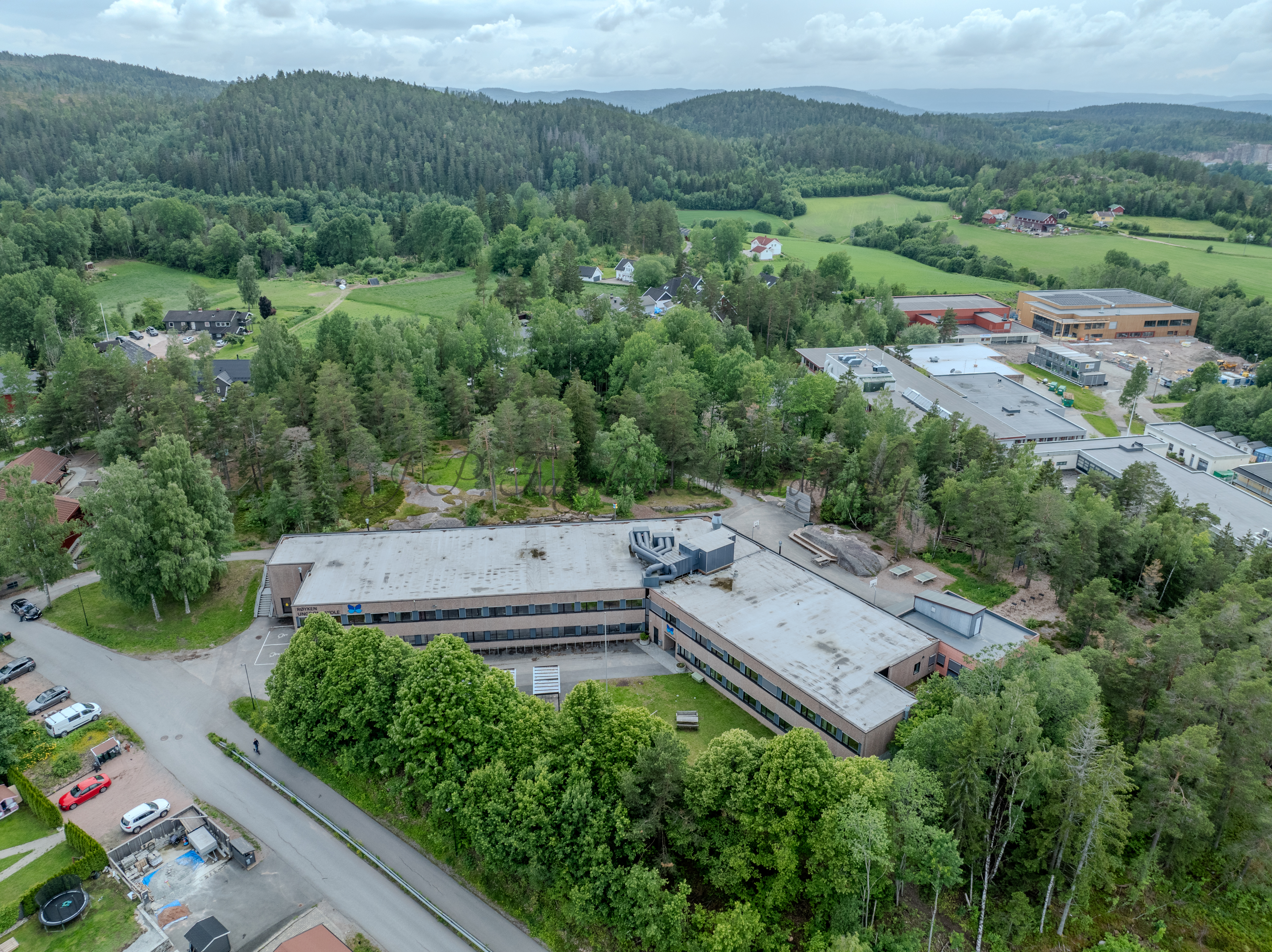 Buildings in a wooded green area under a partially clouded blue sky