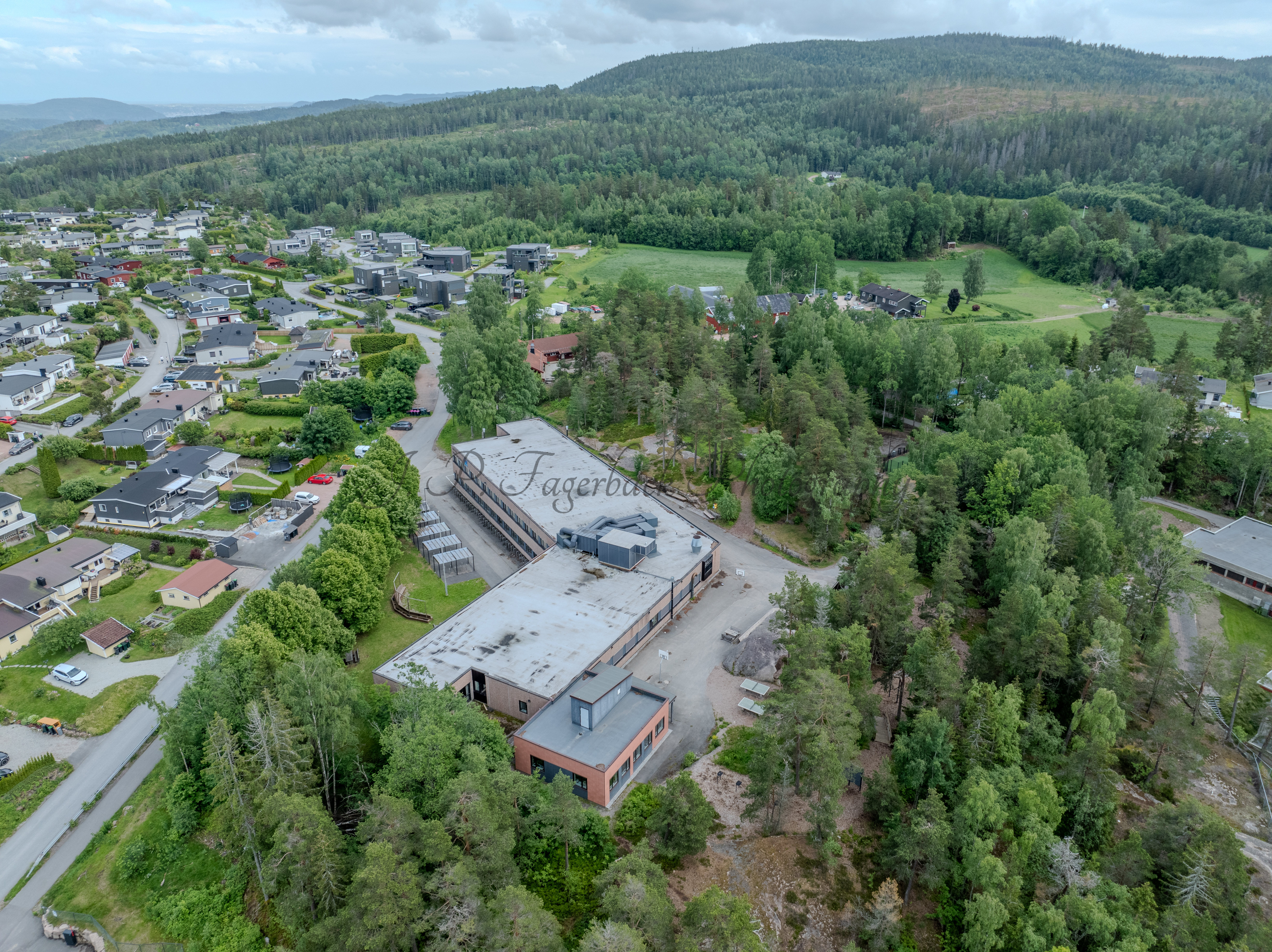 Buildings in a wooded green area under a partially clouded blue sky