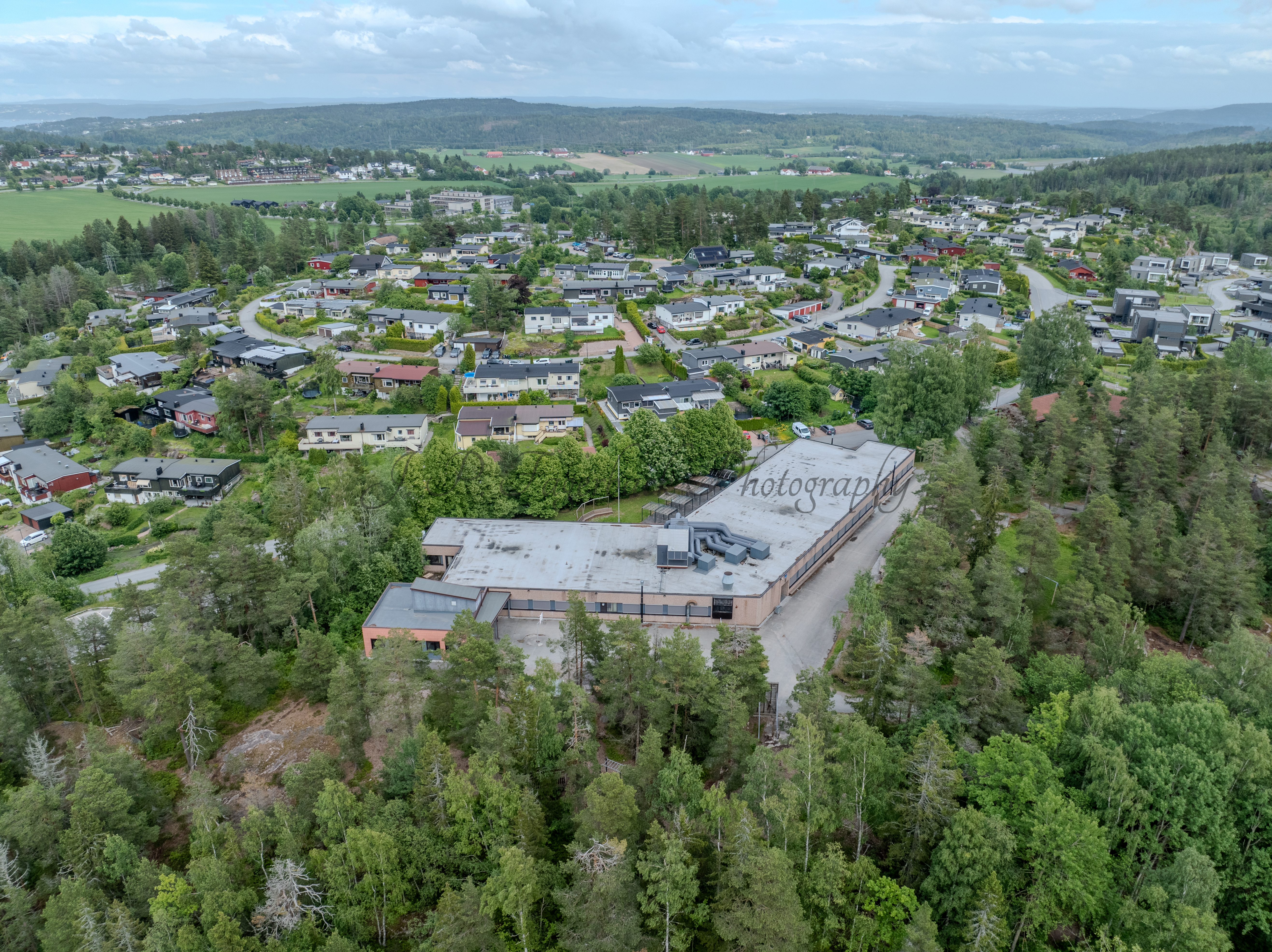 Buildings in a wooded green area under a partially clouded blue sky