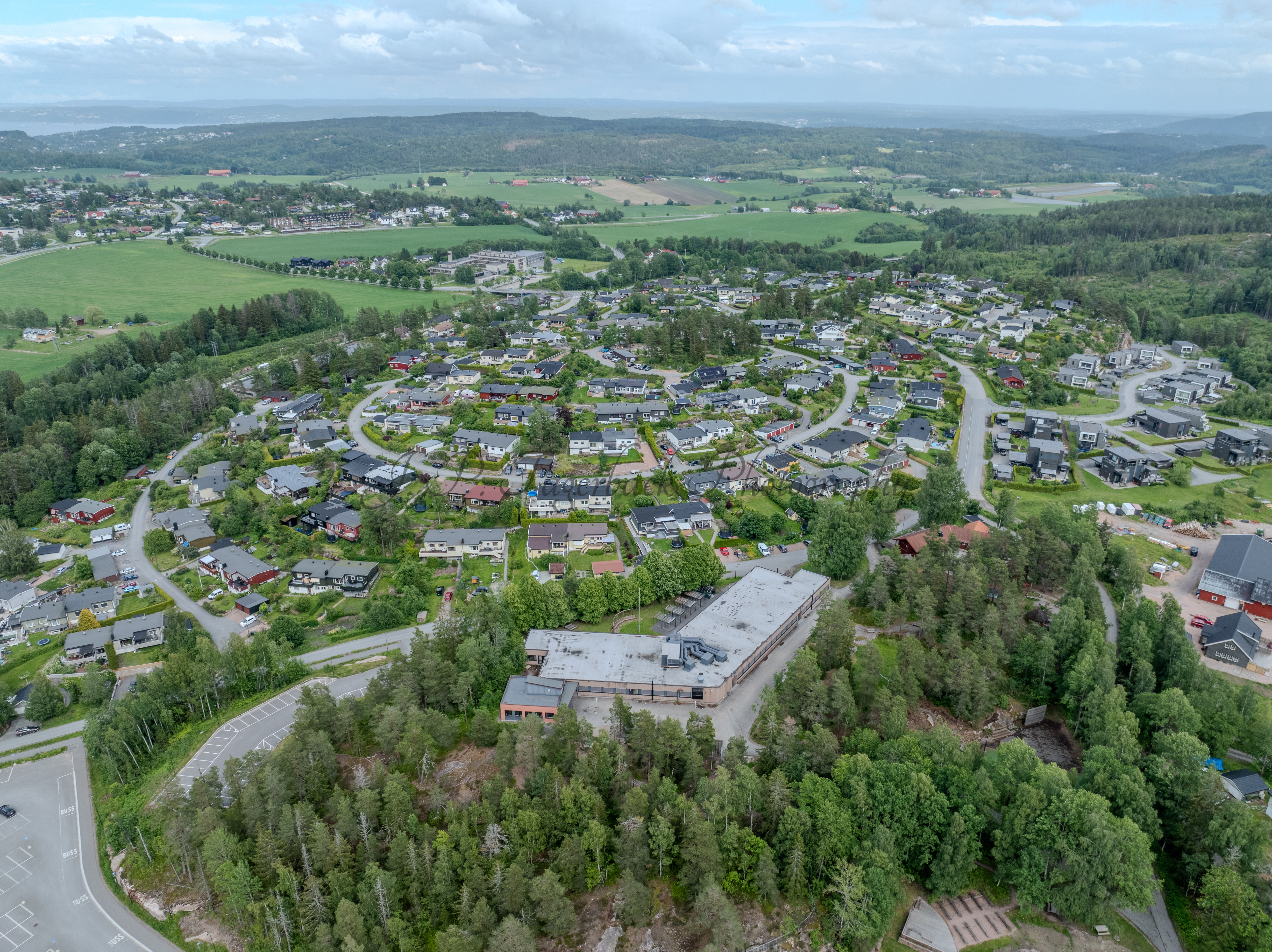 Buildings in a wooded green area under a partially clouded blue sky