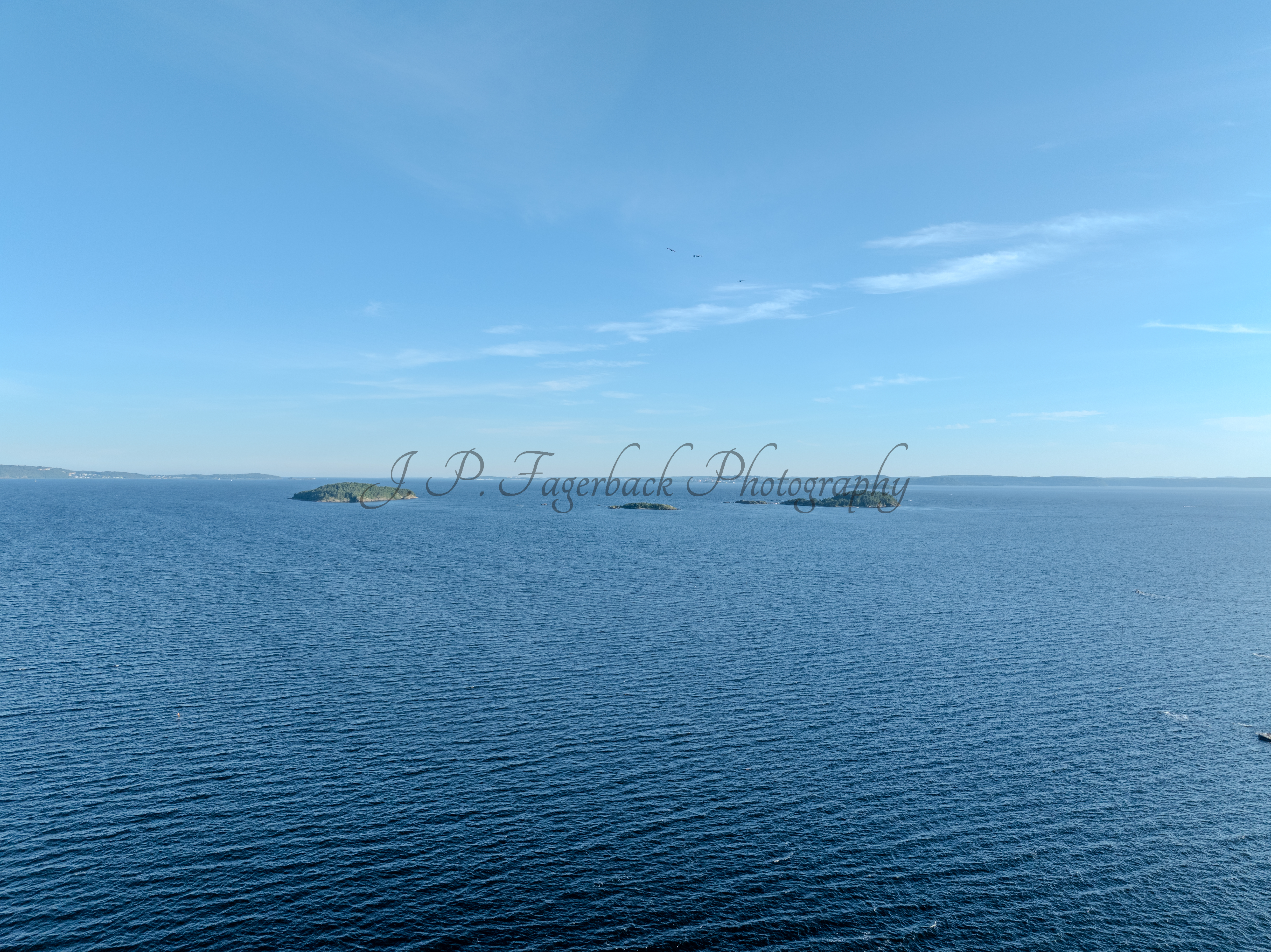 Small islands in a body of blue water under an almost cloudless blue sky