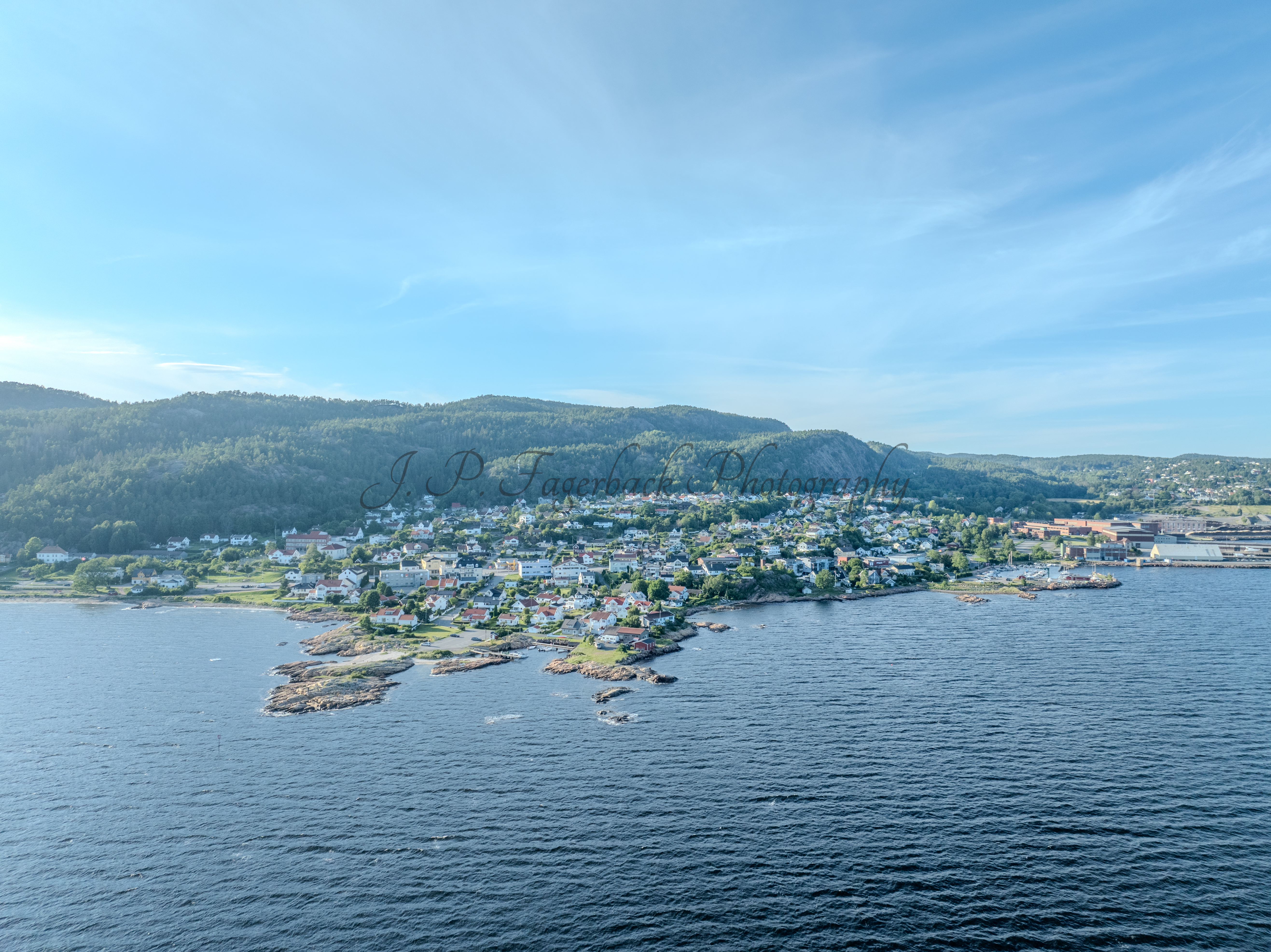 Houses of a town close to a body of water under an almost cloudless sky