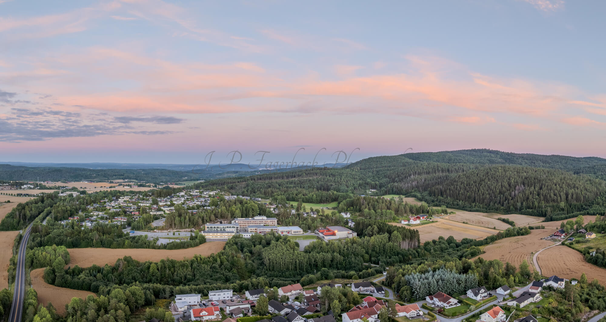 Buildings in a wooded green area under a setting sun