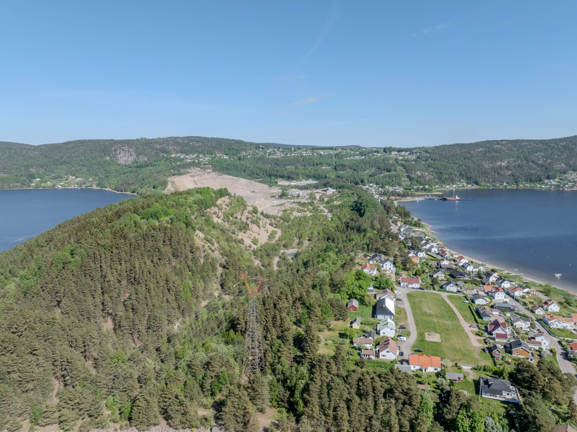 Buildings on both sides of a fjord where a ferry and other smaller boats are sailing