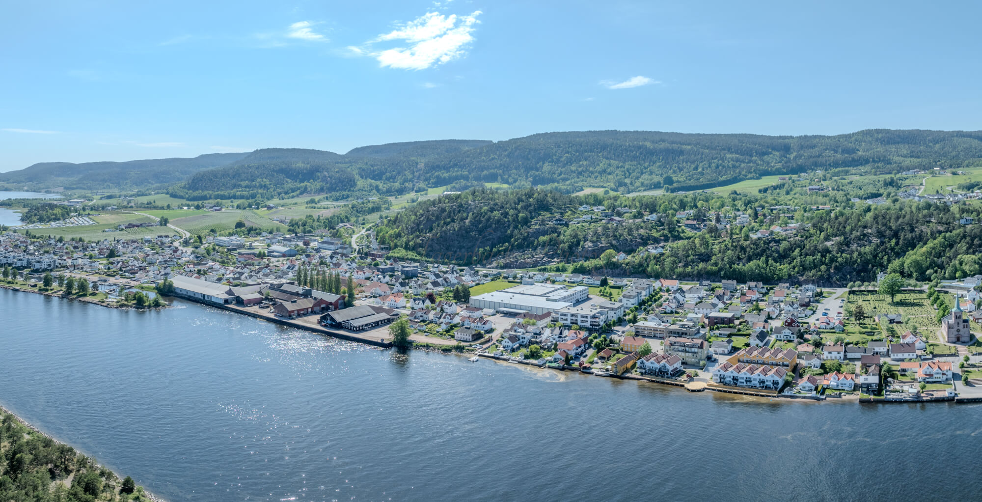 Buildings on both sides of a fjord where a ferry and other smaller boats are sailing