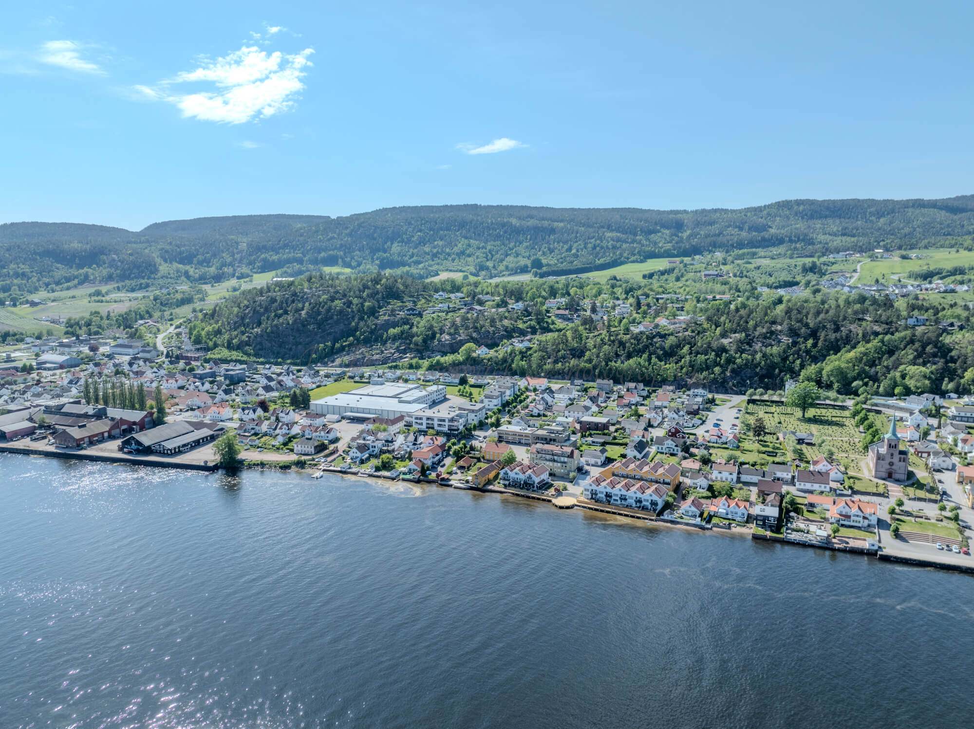 Buildings on both sides of a fjord where a ferry and other smaller boats are sailing