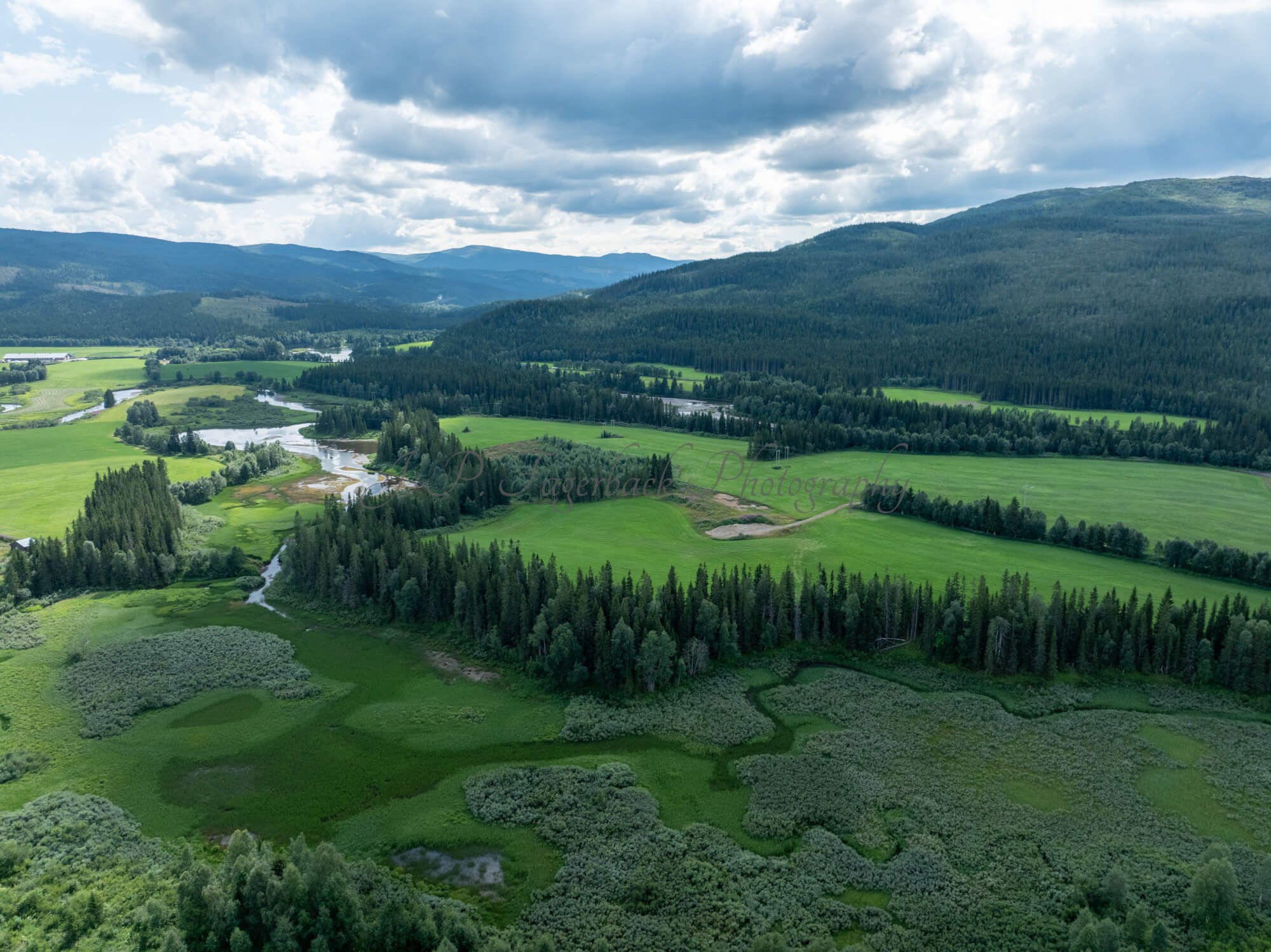 An old airstrip  and fields with buldings beyond it and mountains on the background where one looks like a hat
