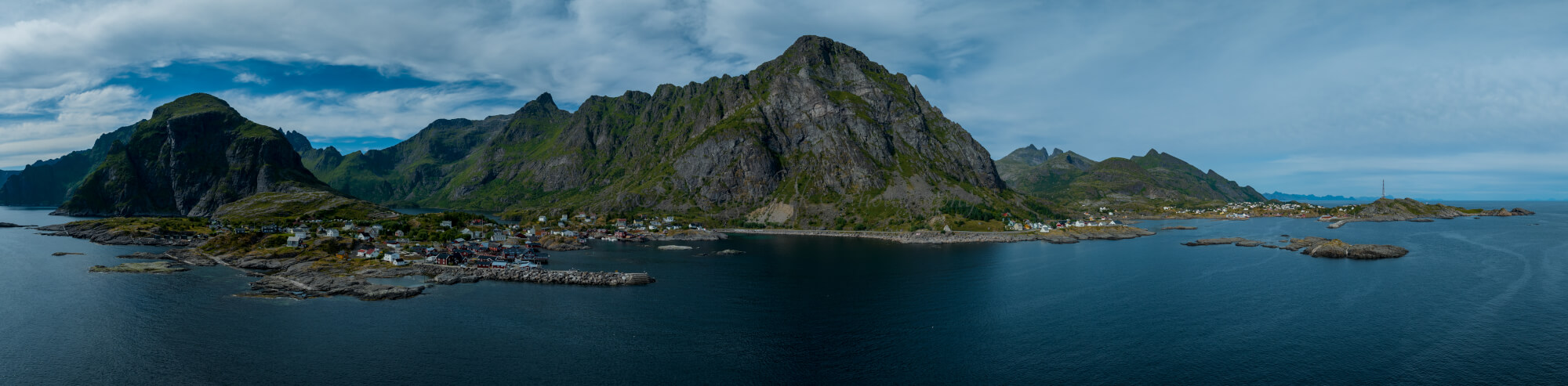 Buildings along the shore of a body of water with a mountain in the background on a gray day