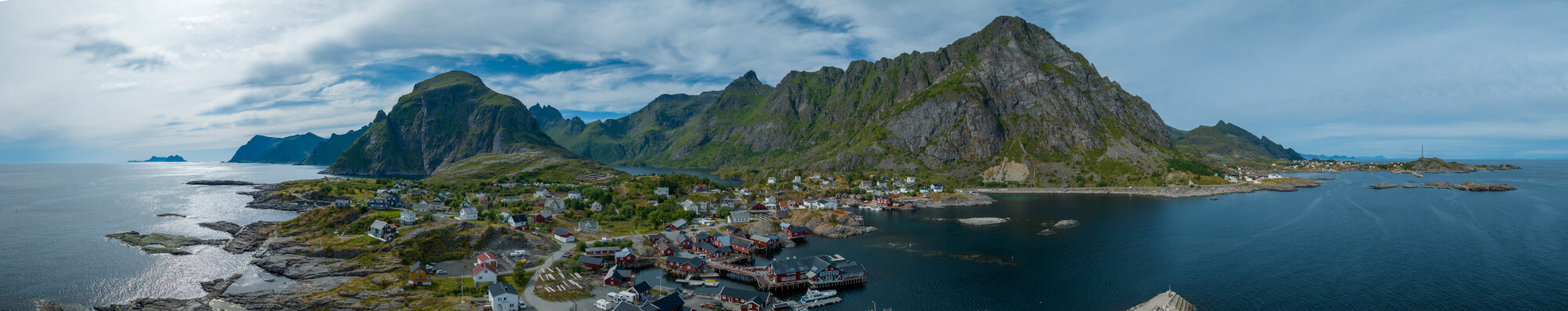 Buildings along the shore of a body of water with a mountain in the background on a gray day