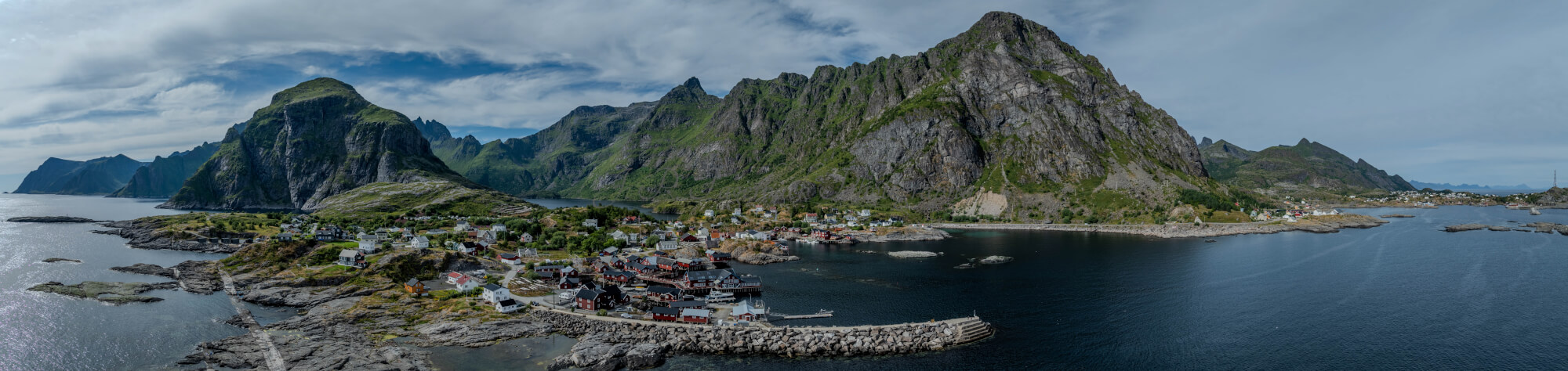 Buildings along the shore of a body of water with a mountain in the background on a gray day