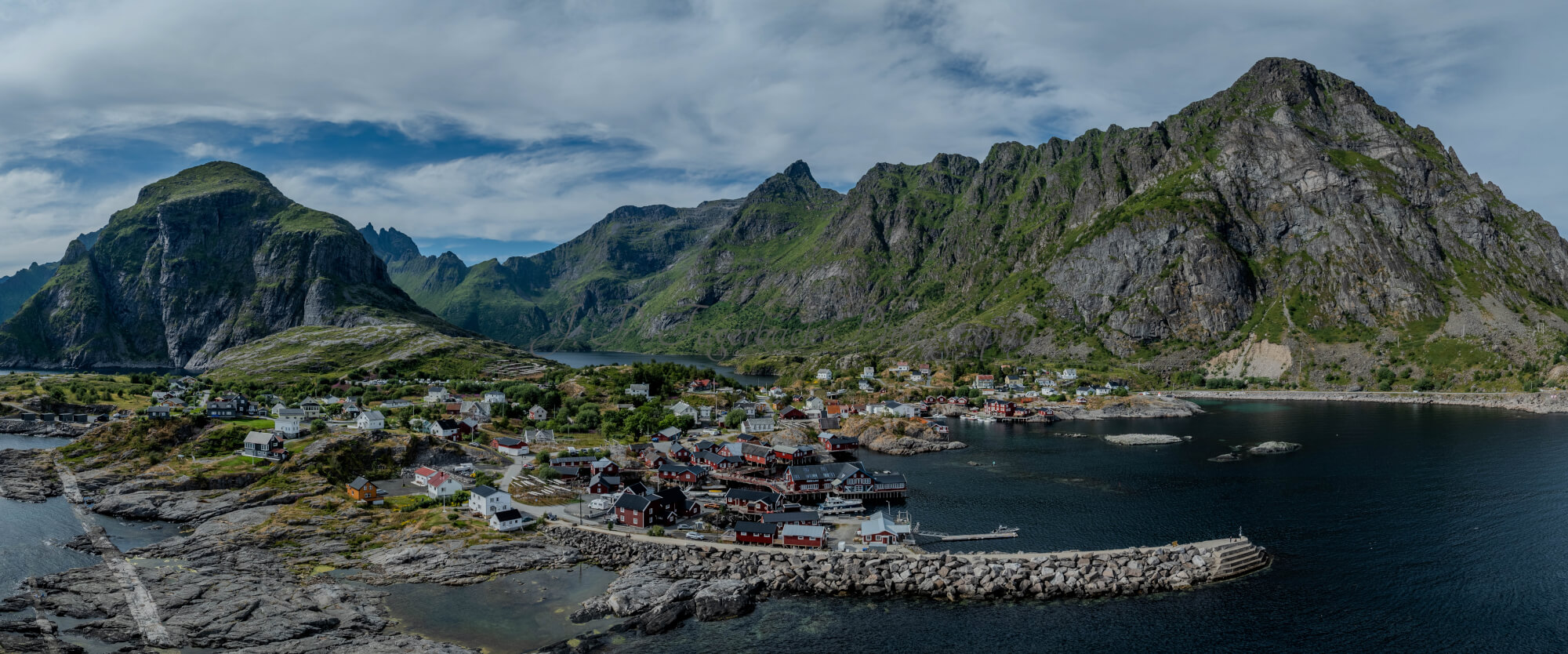 Buildings along the shore of a body of water with a mountain in the background on a gray day