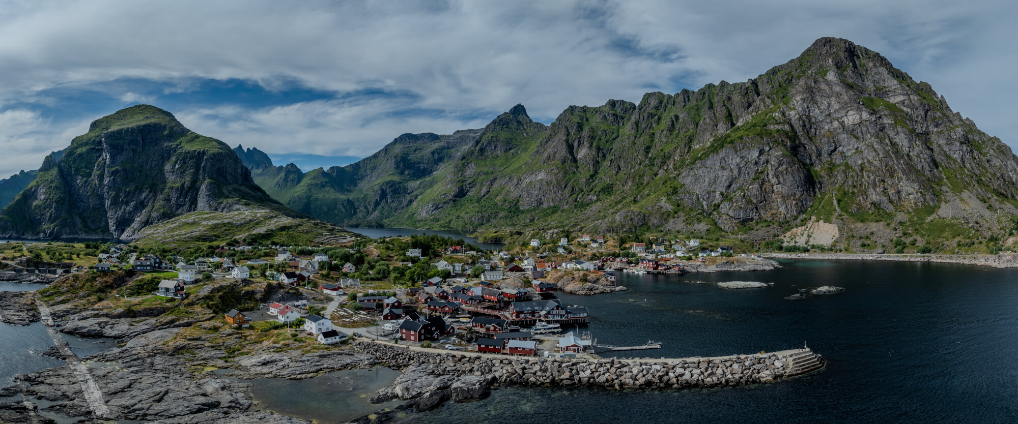 Buildings along the shore of a body of water with a mountain in the background on a gray day