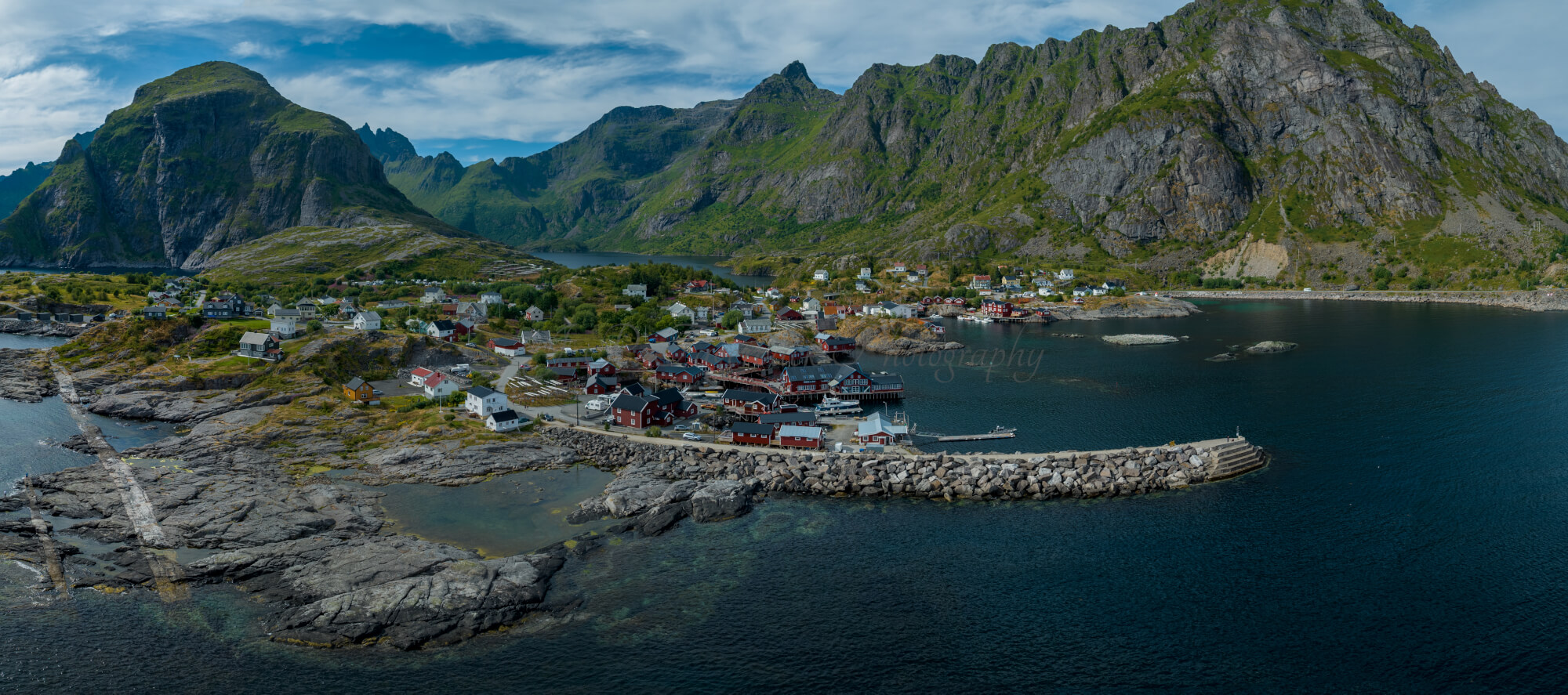 Buildings along the shore of a body of water with a mountain in the background on a gray day