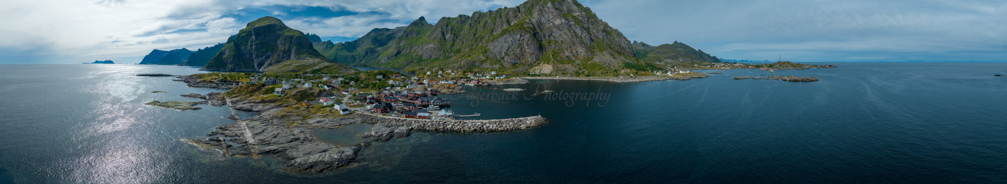 Buildings along the shore of a body of water with a mountain in the background on a gray day