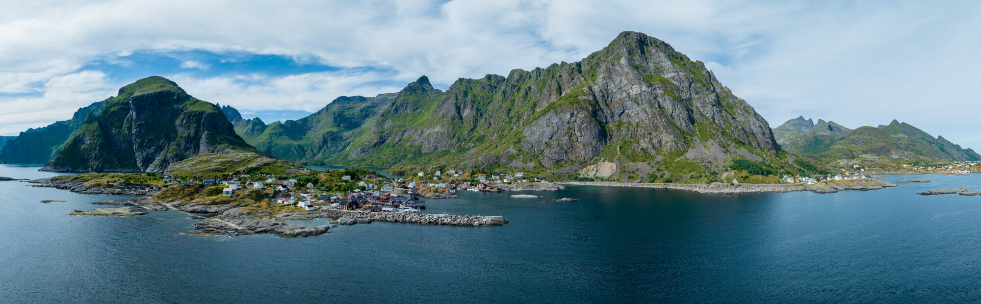 Buildings along the shore of a body of water with a mountain in the background on a gray day