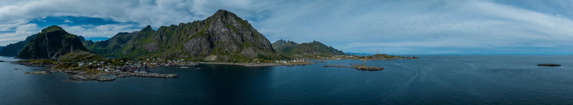 Buildings along the shore of a body of water with a mountain in the background on a gray day