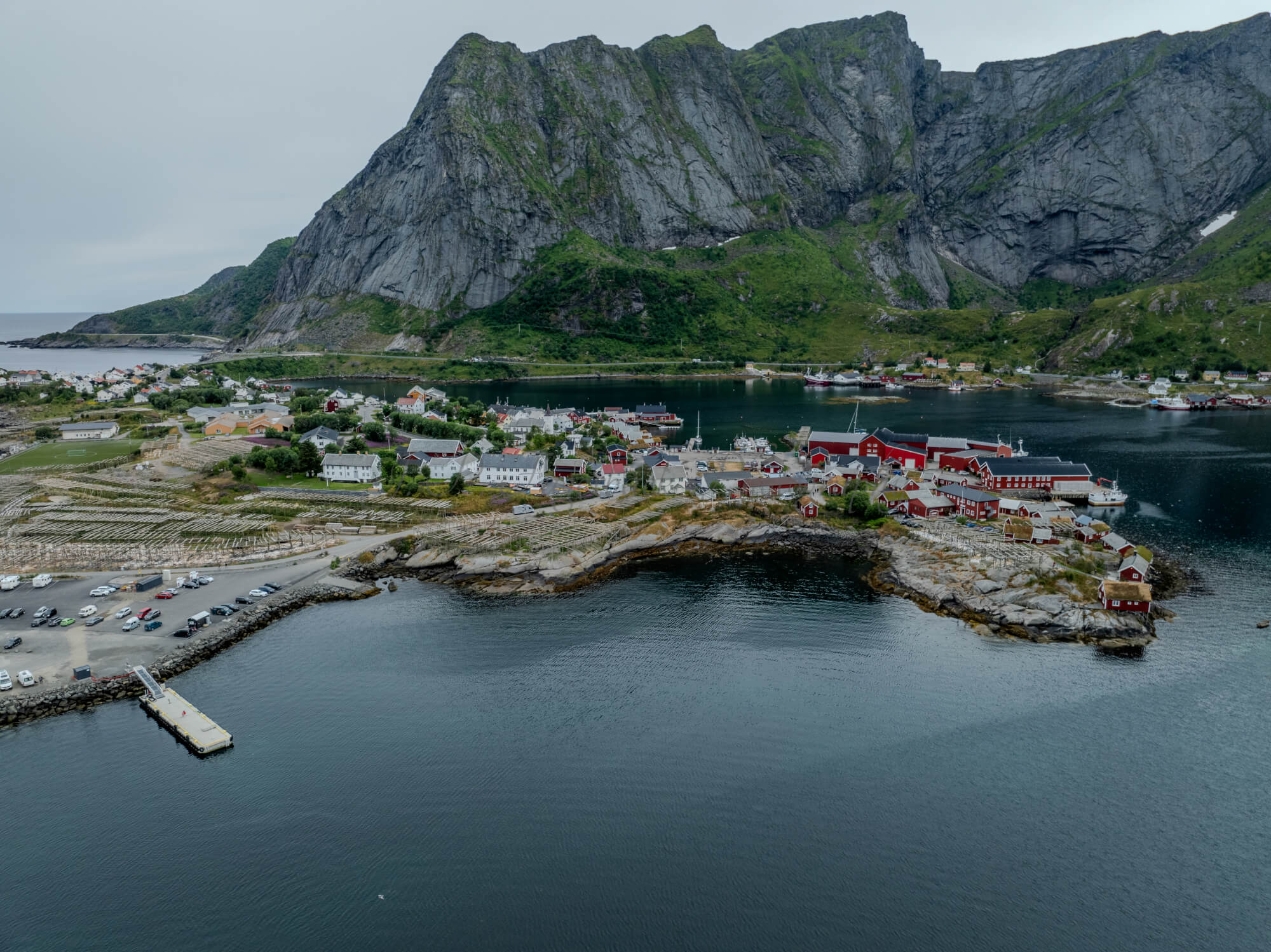 Buildings along the shore of a body of water with a mountain in the background on a gray day