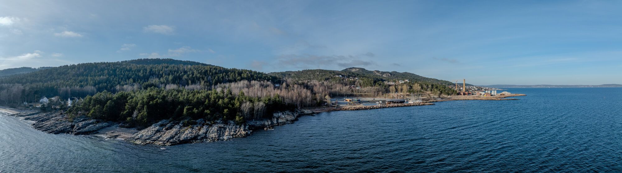 An old ship  wreck with a protection roof over it in a marina by a large body of water under a blue sky