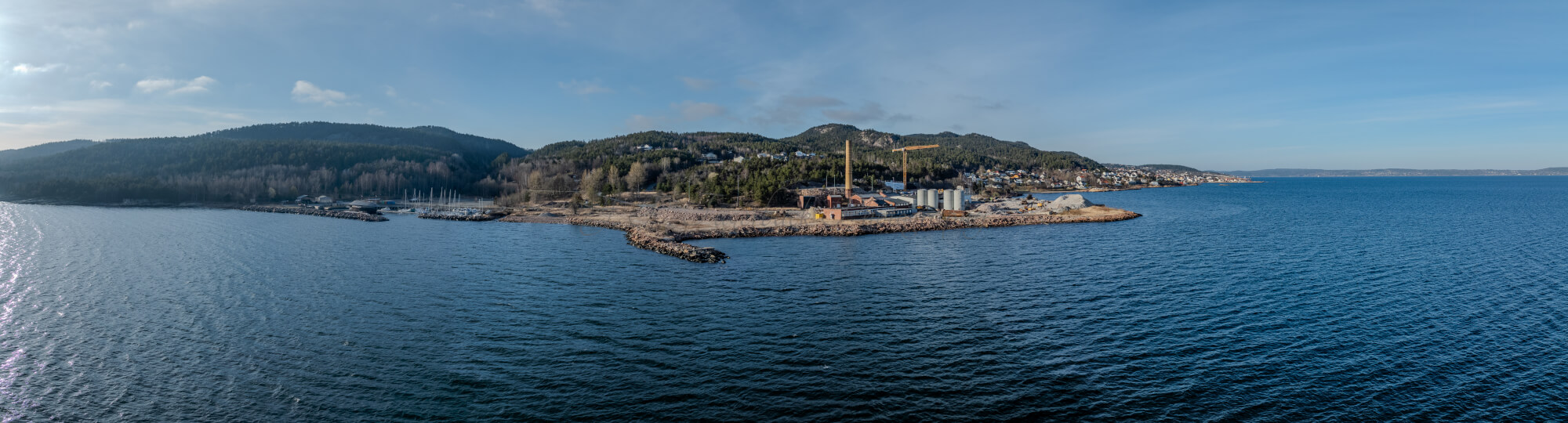 An old ship  wreck with a protection roof over it in a marina by a large body of water under a blue sky