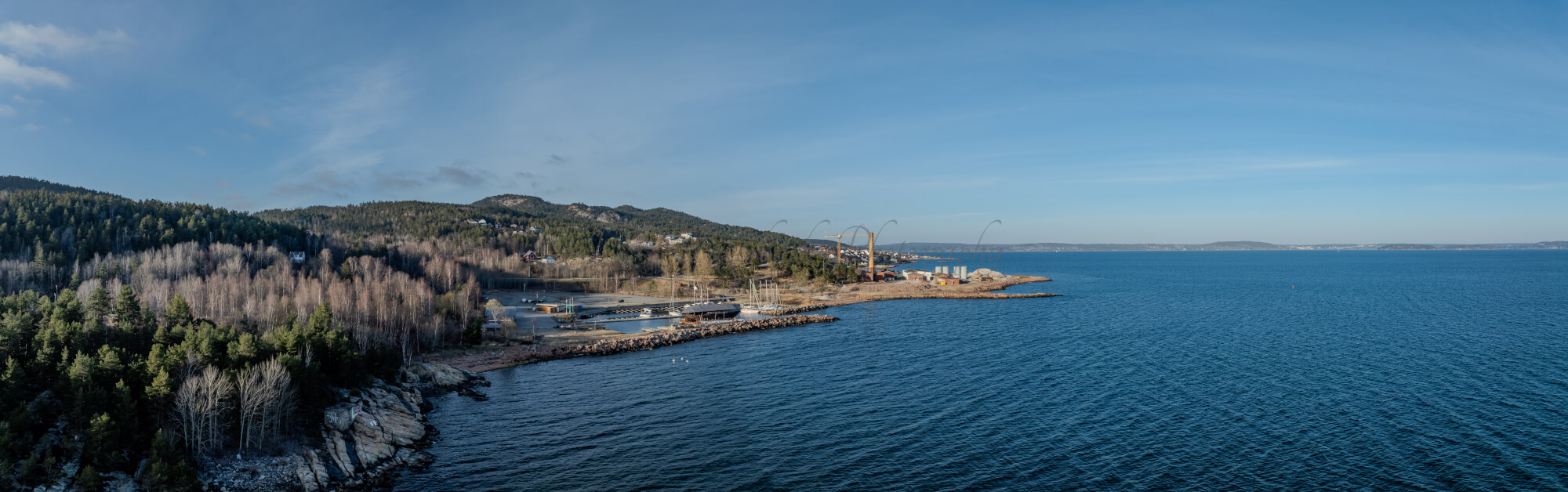 An old ship  wreck with a protection roof over it in a marina by a large body of water under a blue sky