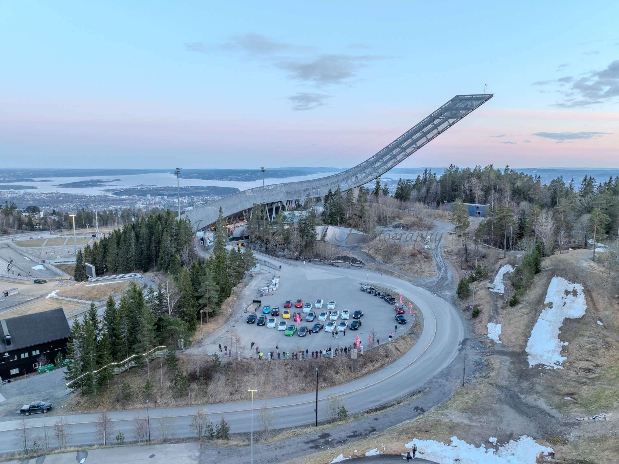 Cars on a parking lot from upon high with a ski jump in the background