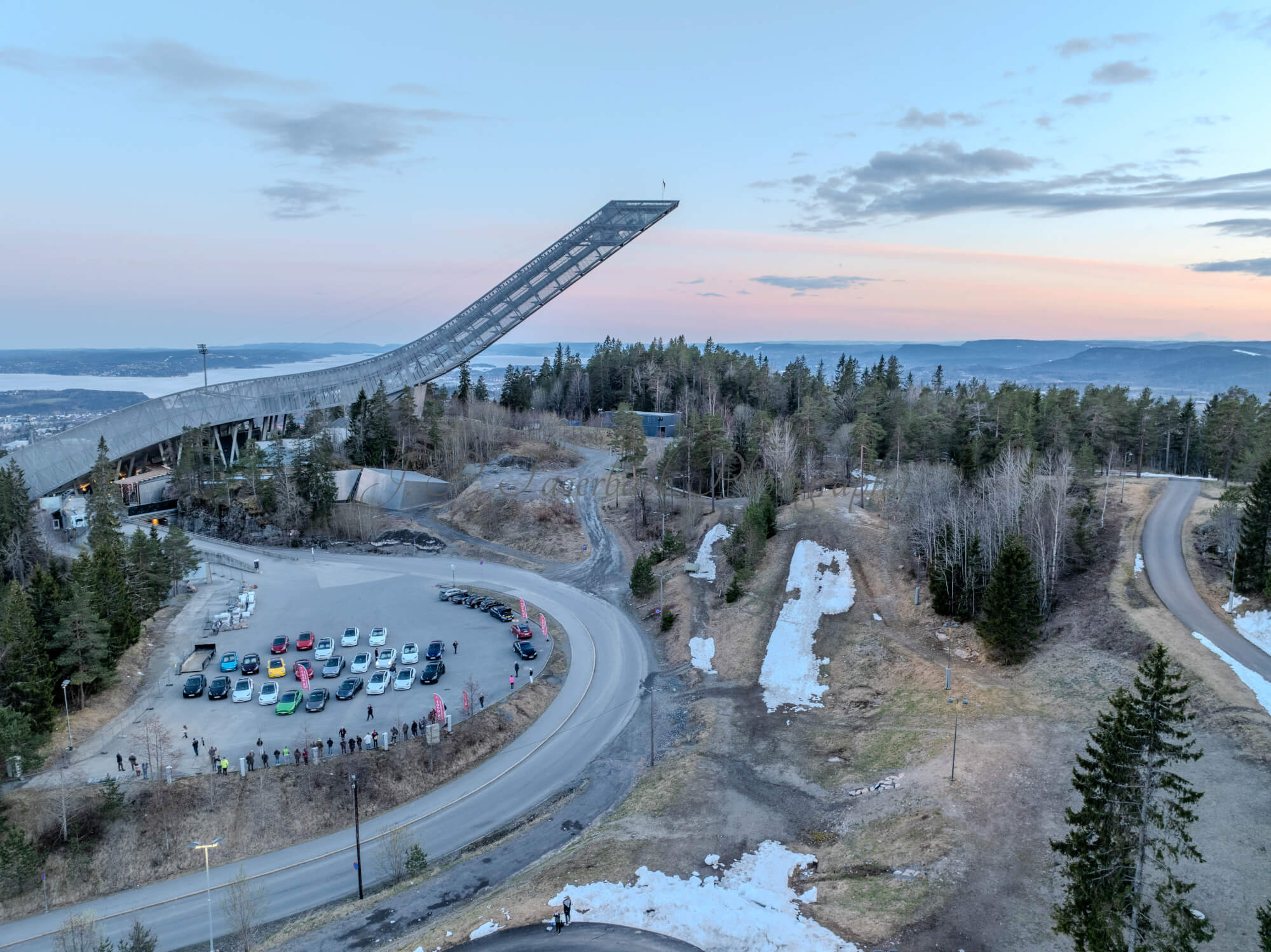 Cars on a parking lot from upon high with a ski jump in the background