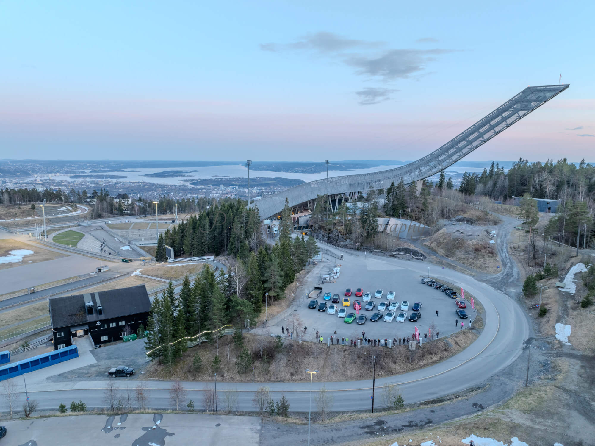 Cars on a parking lot from upon high with a ski jump in the background