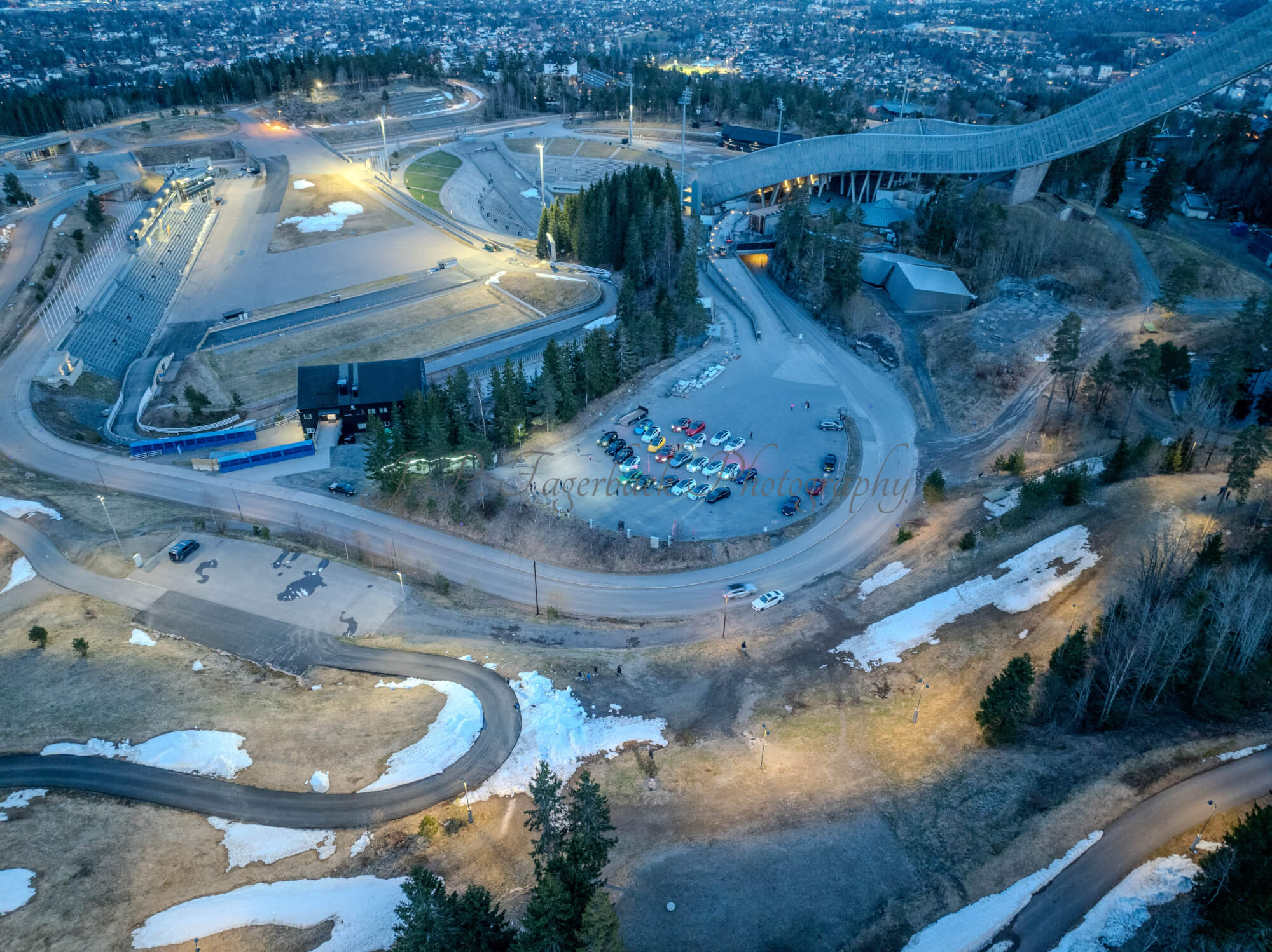 Cars on a parking lot from upon high with a ski jump in the background