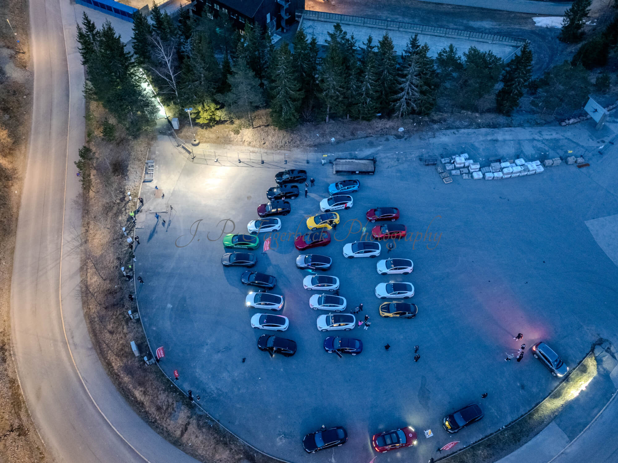 Cars on a parking lot from upon high with a ski jump in the background