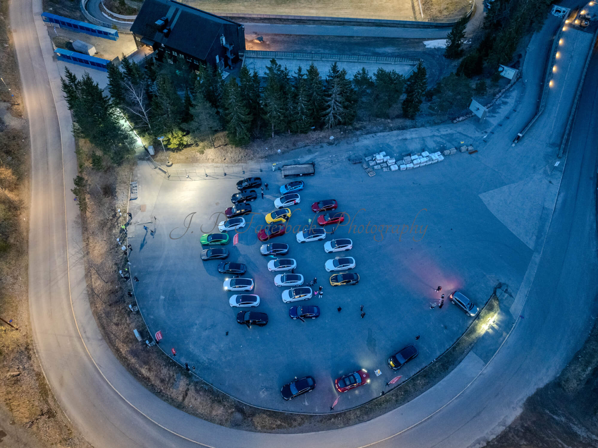 Cars on a parking lot from upon high with a ski jump in the background