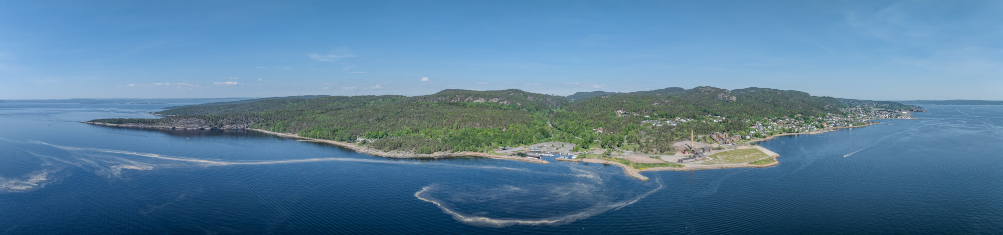 An old ship  wreck with a protection roof over it in a marina by a large body of water under a blue sky