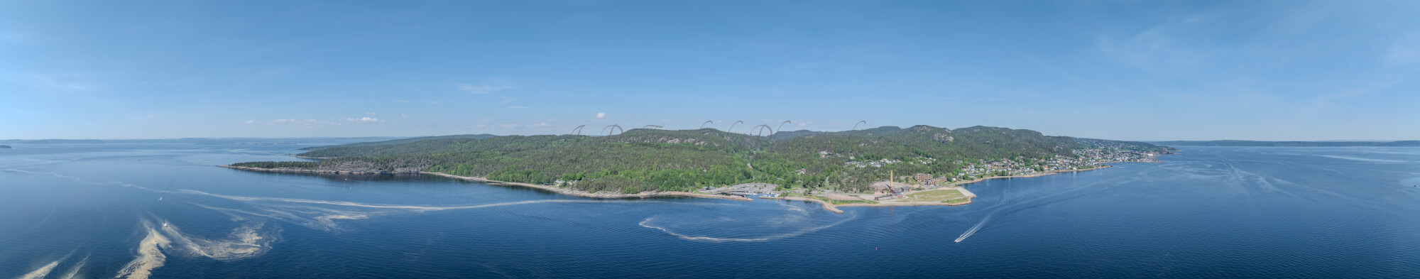 An old ship  wreck with a protection roof over it in a marina by a large body of water under a blue sky