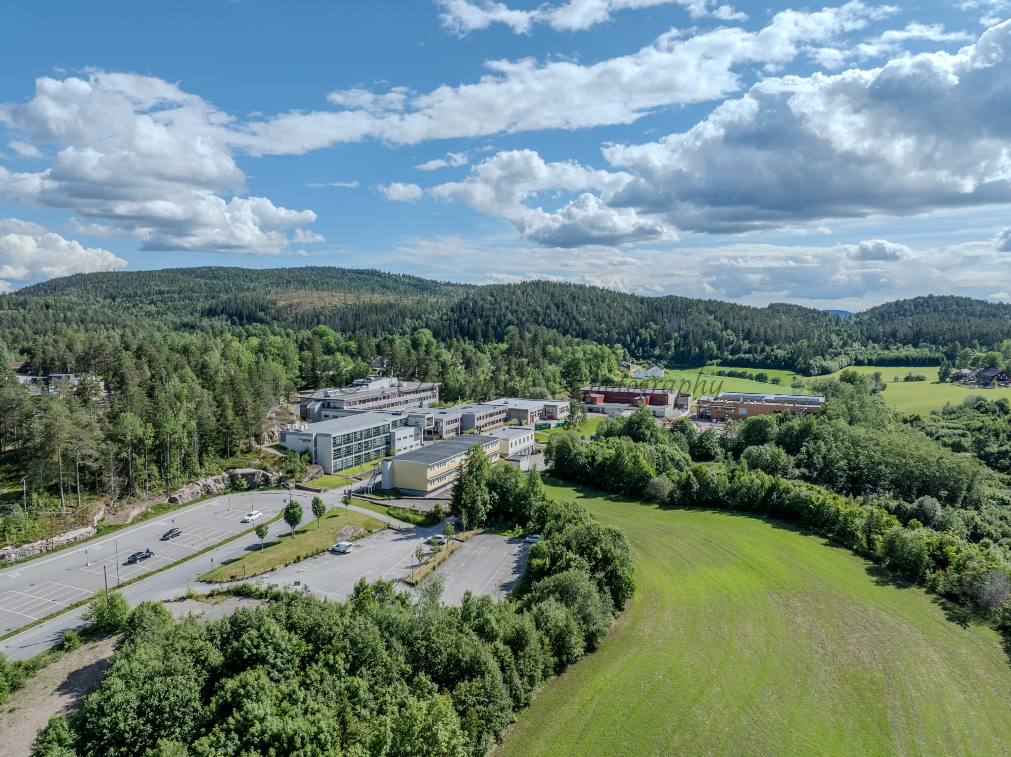 Buildings in a wooded green area under a partially clouded blue sky